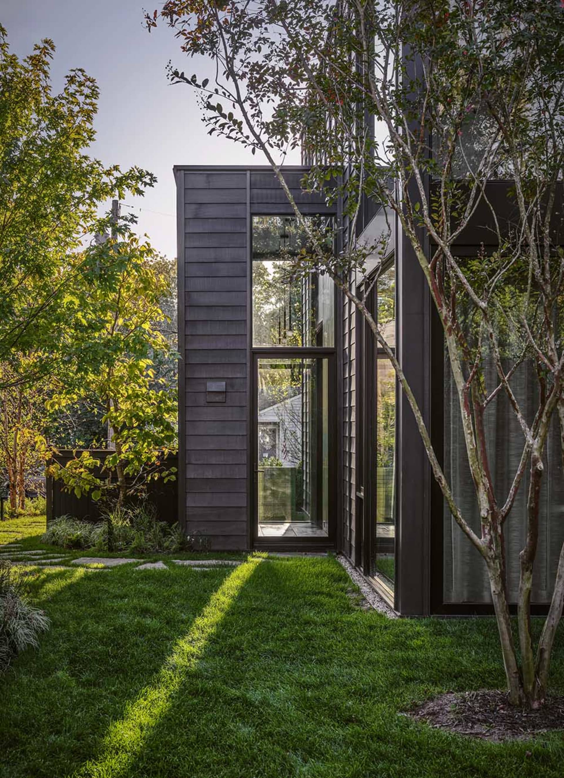 Modern architectural extension with wooden cladding and large glass windows in a residential backyard setting.