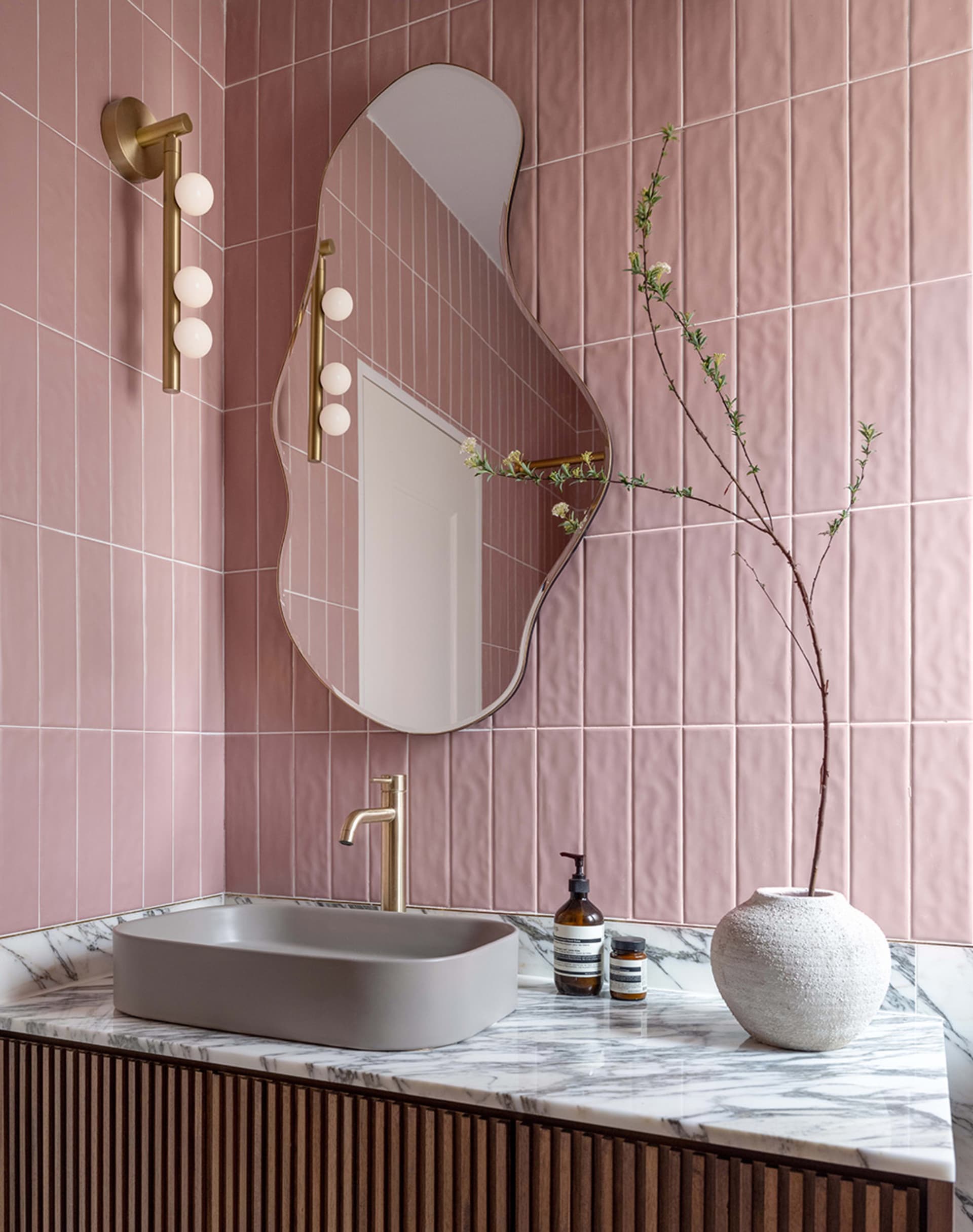 Modern minimalist bathroom with pink textured tiles and marble countertop with a sink and faucet.