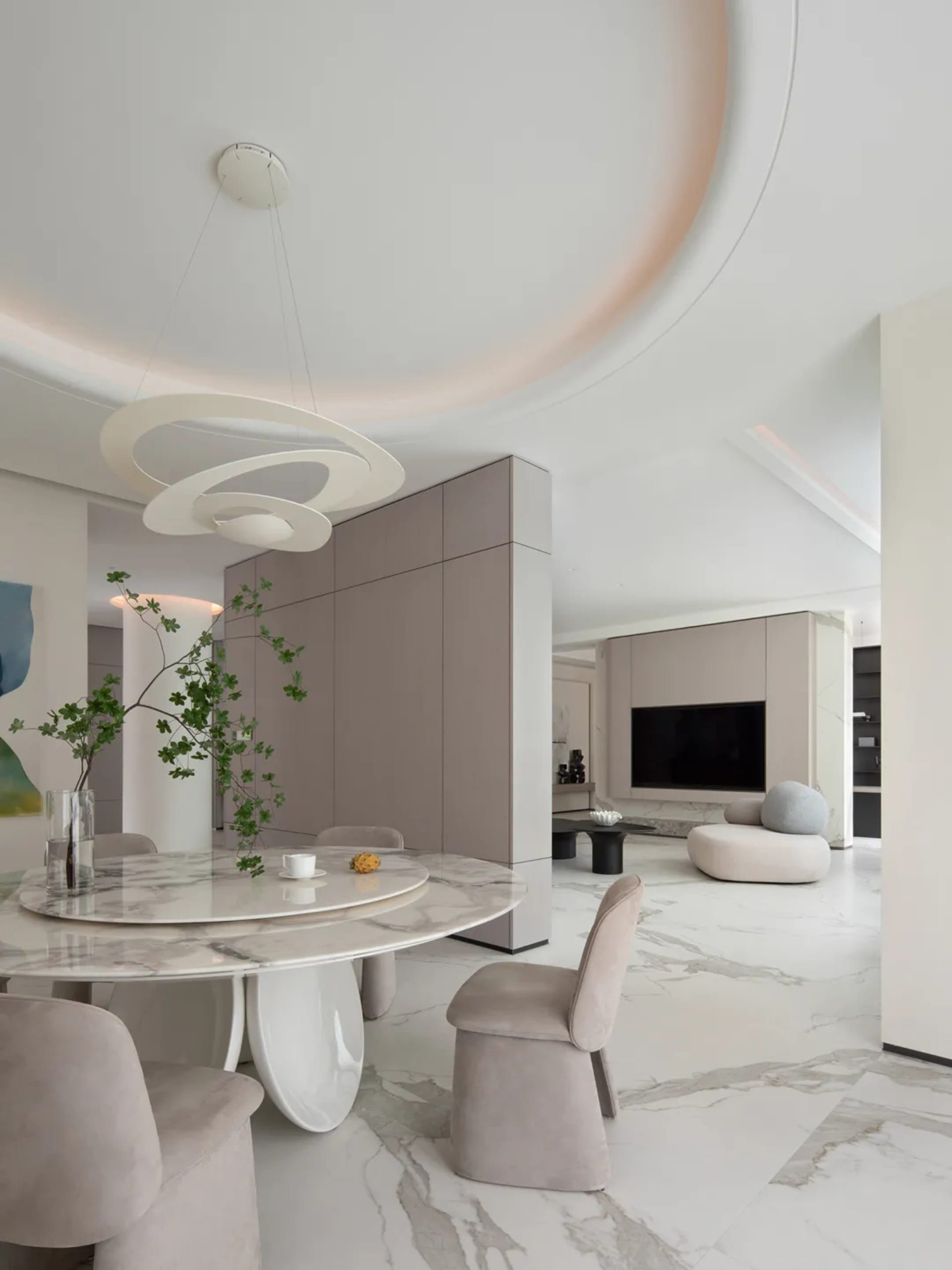 Modern minimalist living room with marble finishes, featuring a sleek, round dining table and contemporary seating.