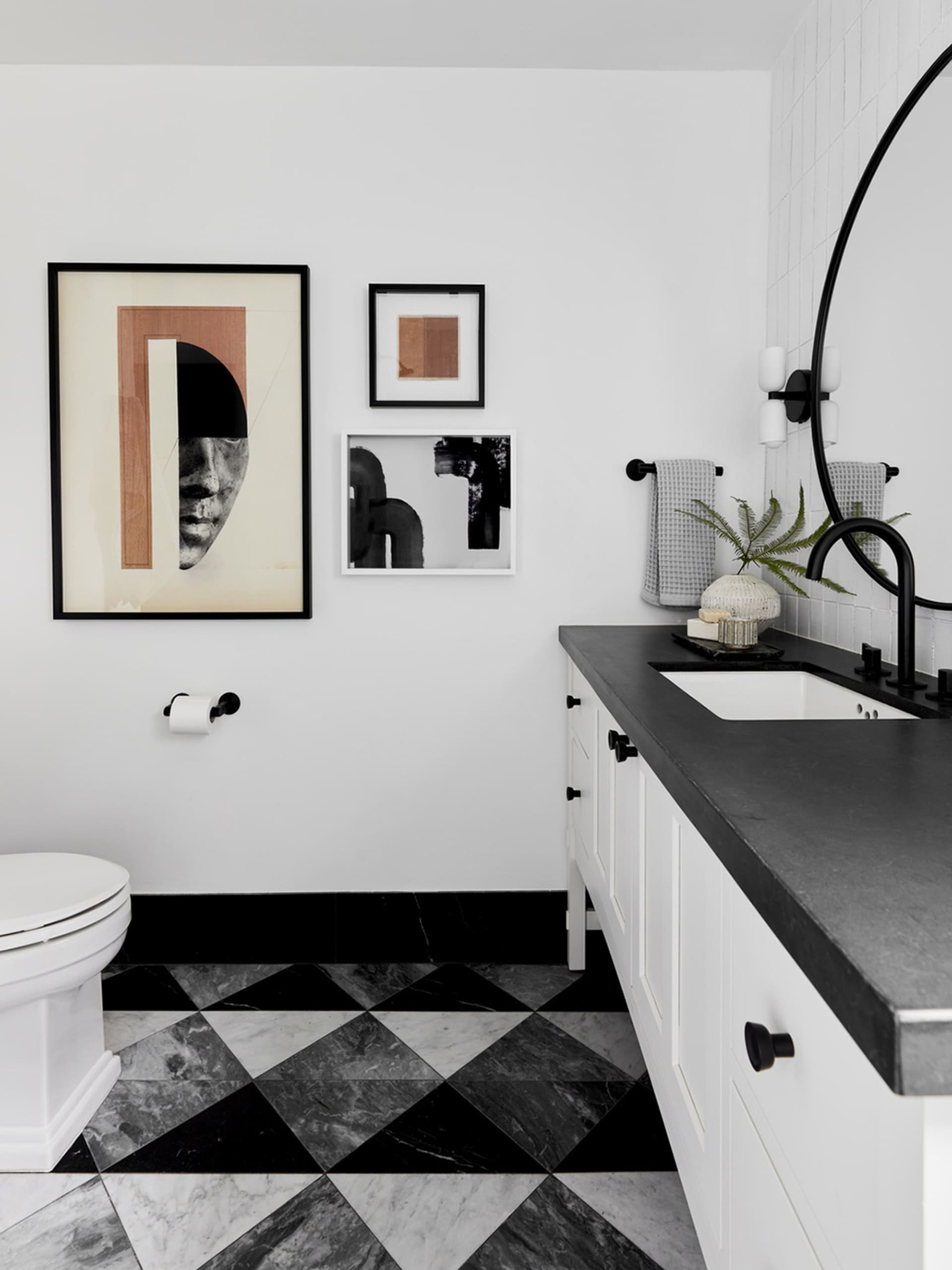 Minimalist bathroom featuring black and white checkered marble tiles, a white ceramic toilet, a white vanity with black count