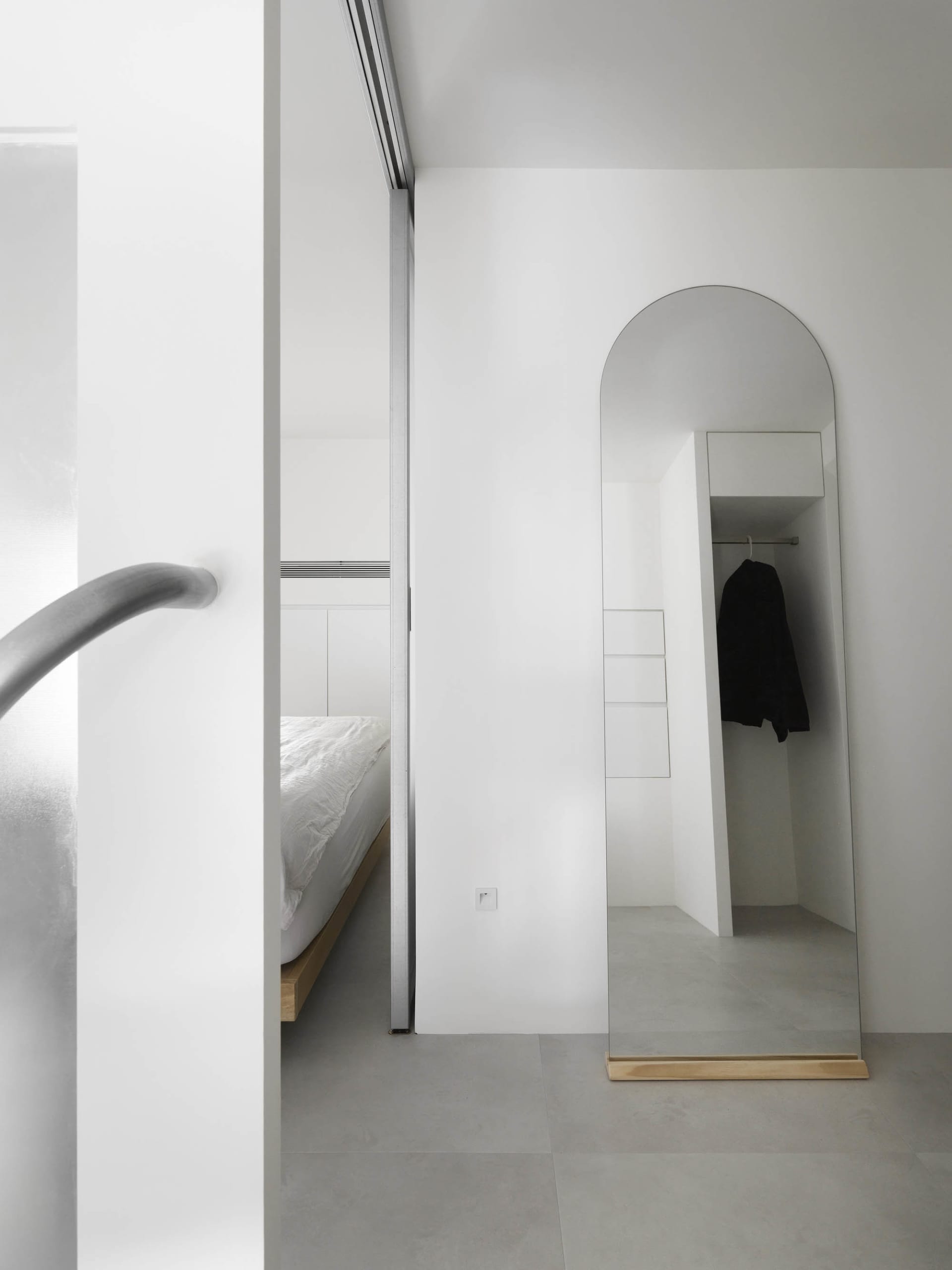 Minimalist bedroom interior with metallic accents and concrete floor.