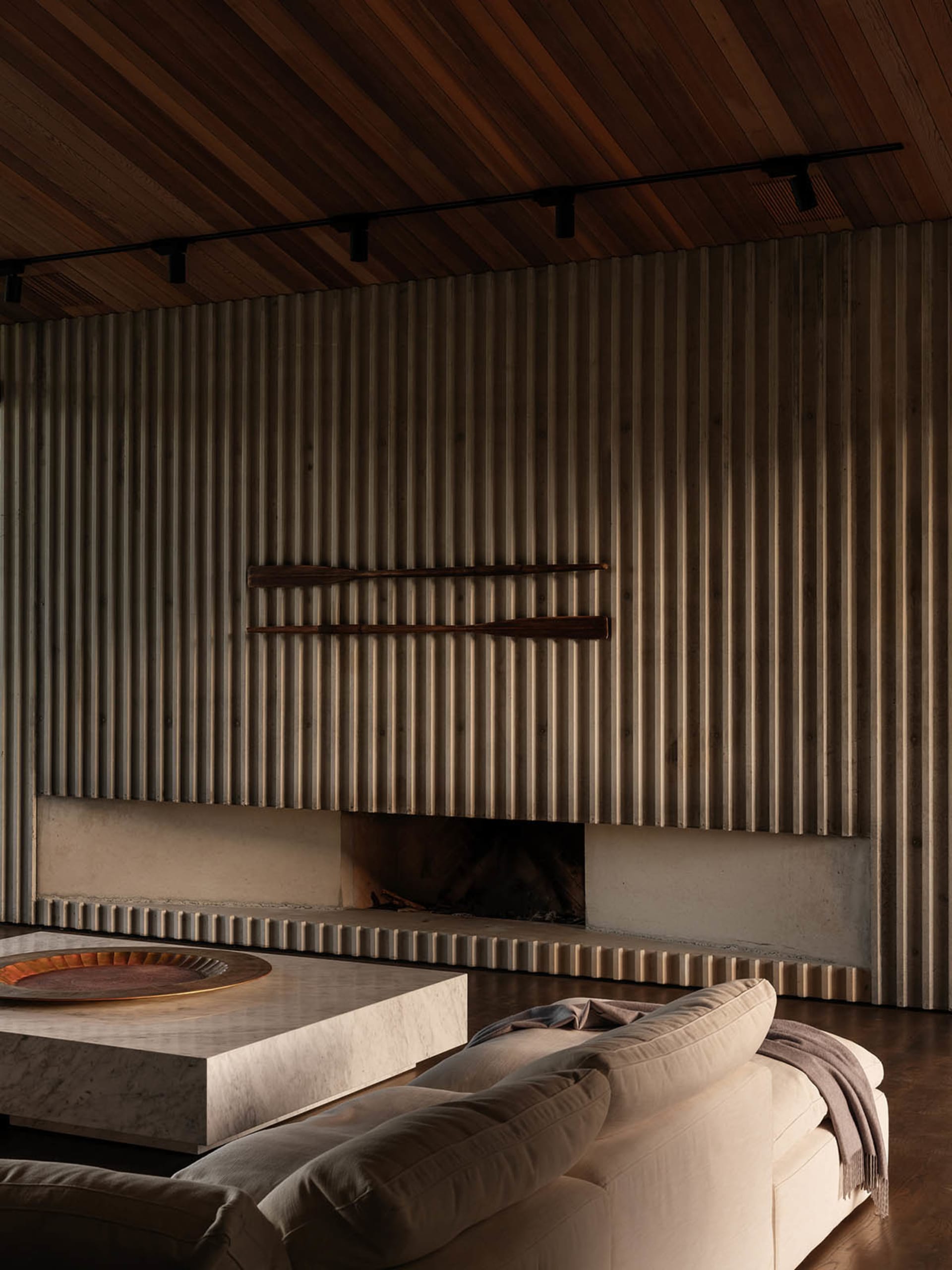 A minimalist living room featuring wood elements and a corrugated metal fireplace wall.