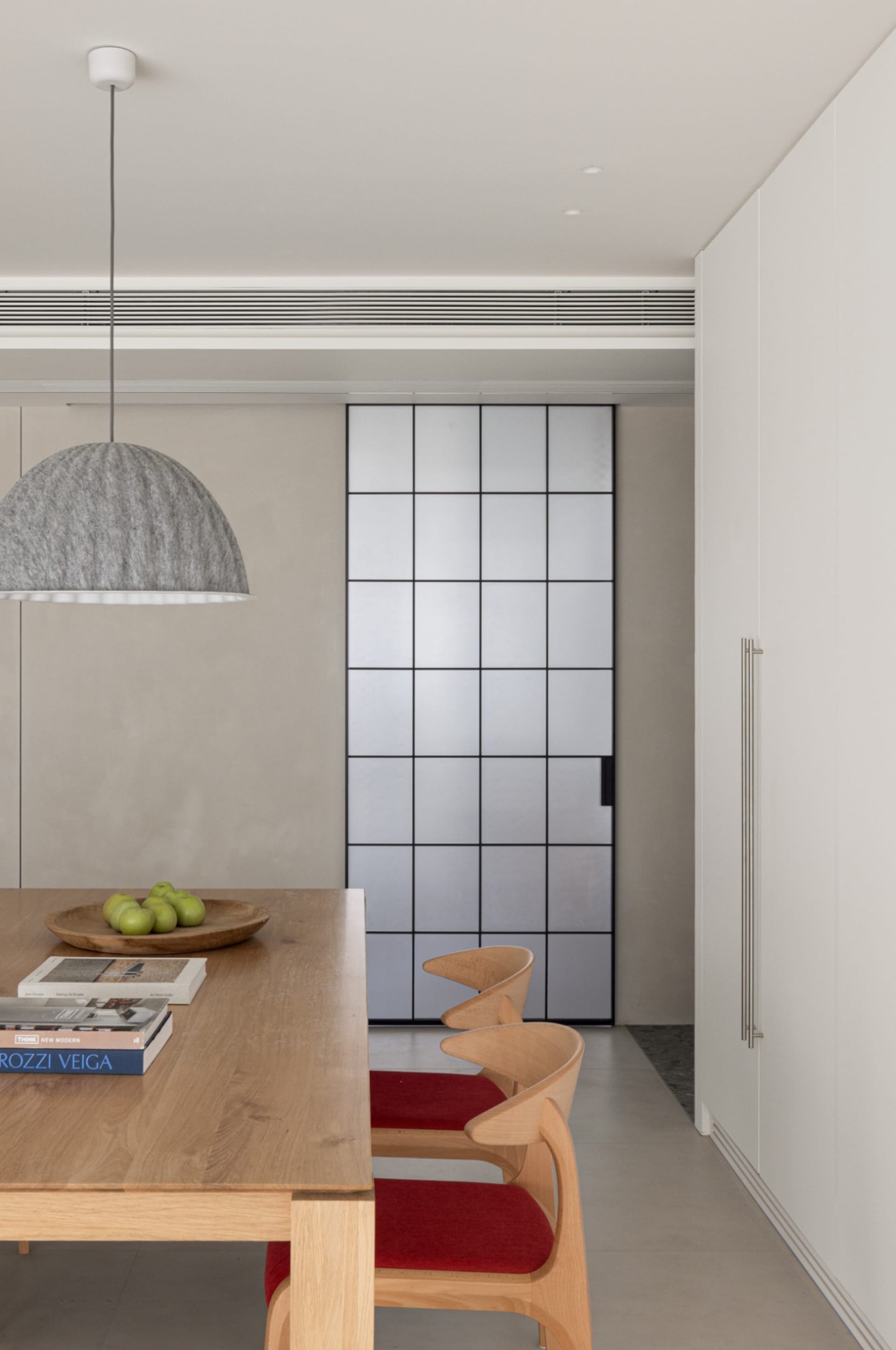 Modern minimalist kitchen features sleek wooden furniture and a geometric glass divider.