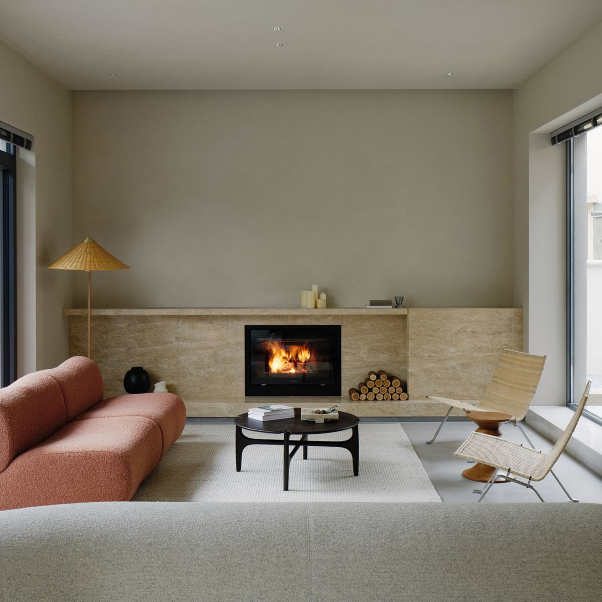 Modern minimalist living room with a concrete fireplace, orange sofa, and white chairs.