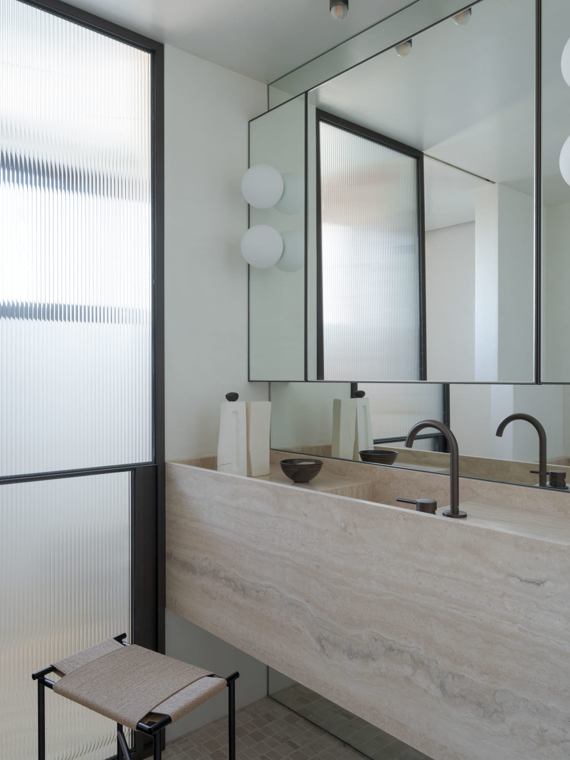Modern bathroom with stone interior design, featuring a large sink and large mirror.
