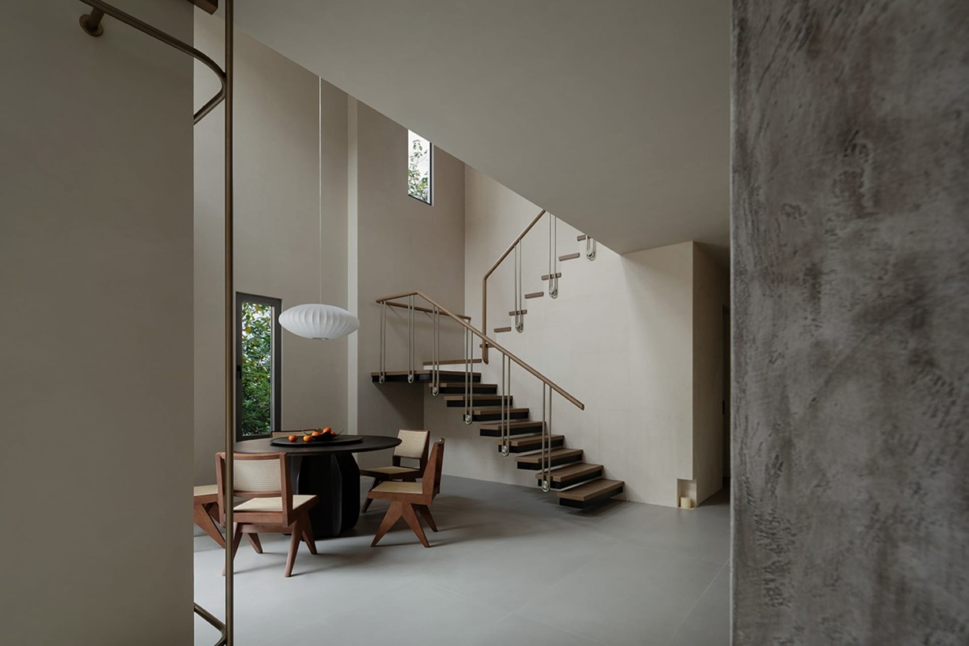 A modern interior featuring concrete floating stairs and minimalist furniture.