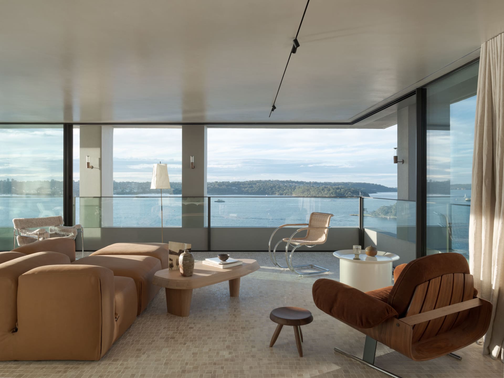 A modern minimalist living room with a glass window overlooking a serene ocean view.