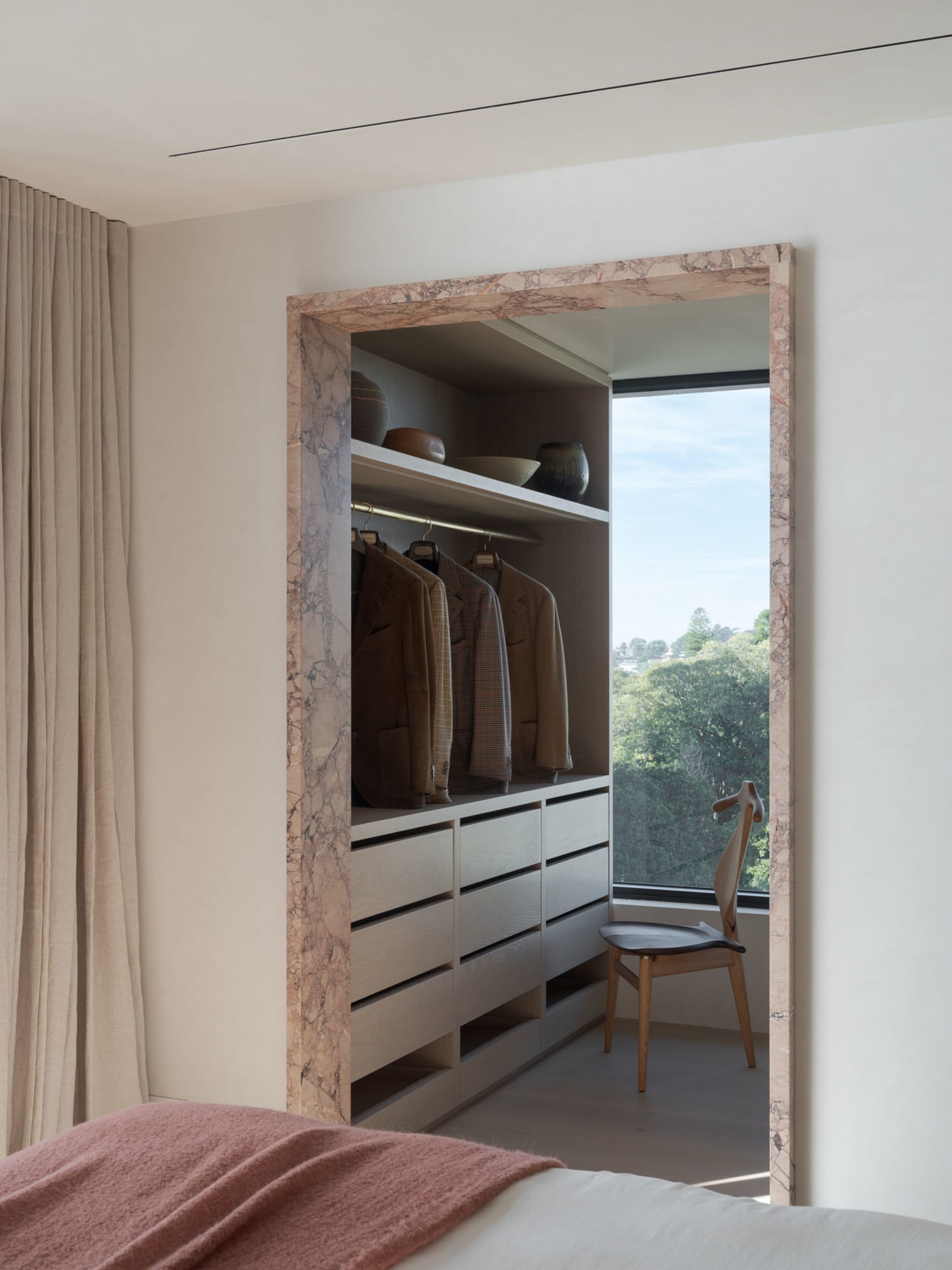 Modern wardrobe with marble and wooden elements, featuring a view of greenery.