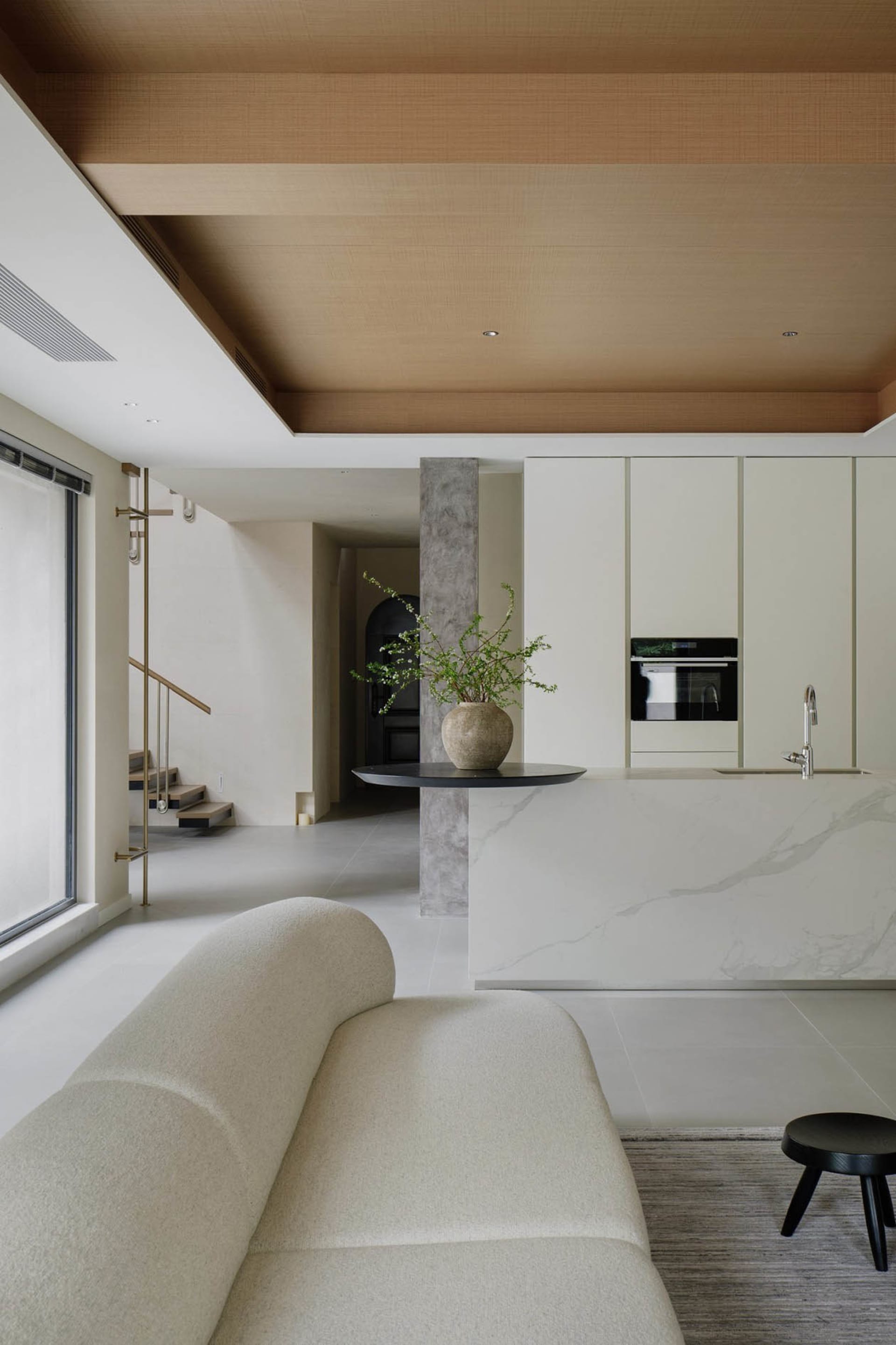 Modern minimalist living room with marble accent wall, white sofa, and black accents.