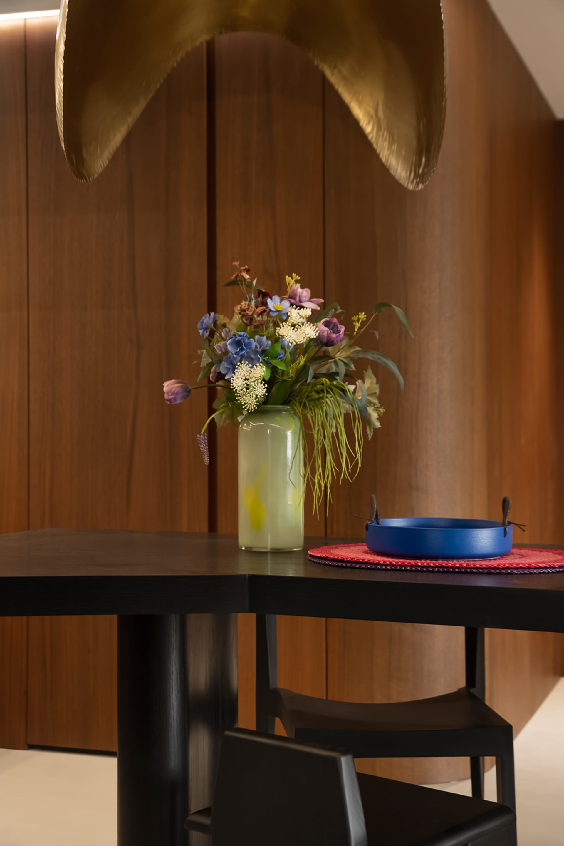 A modern dining room featuring a wooden table adorned with a vase of fresh flowers.