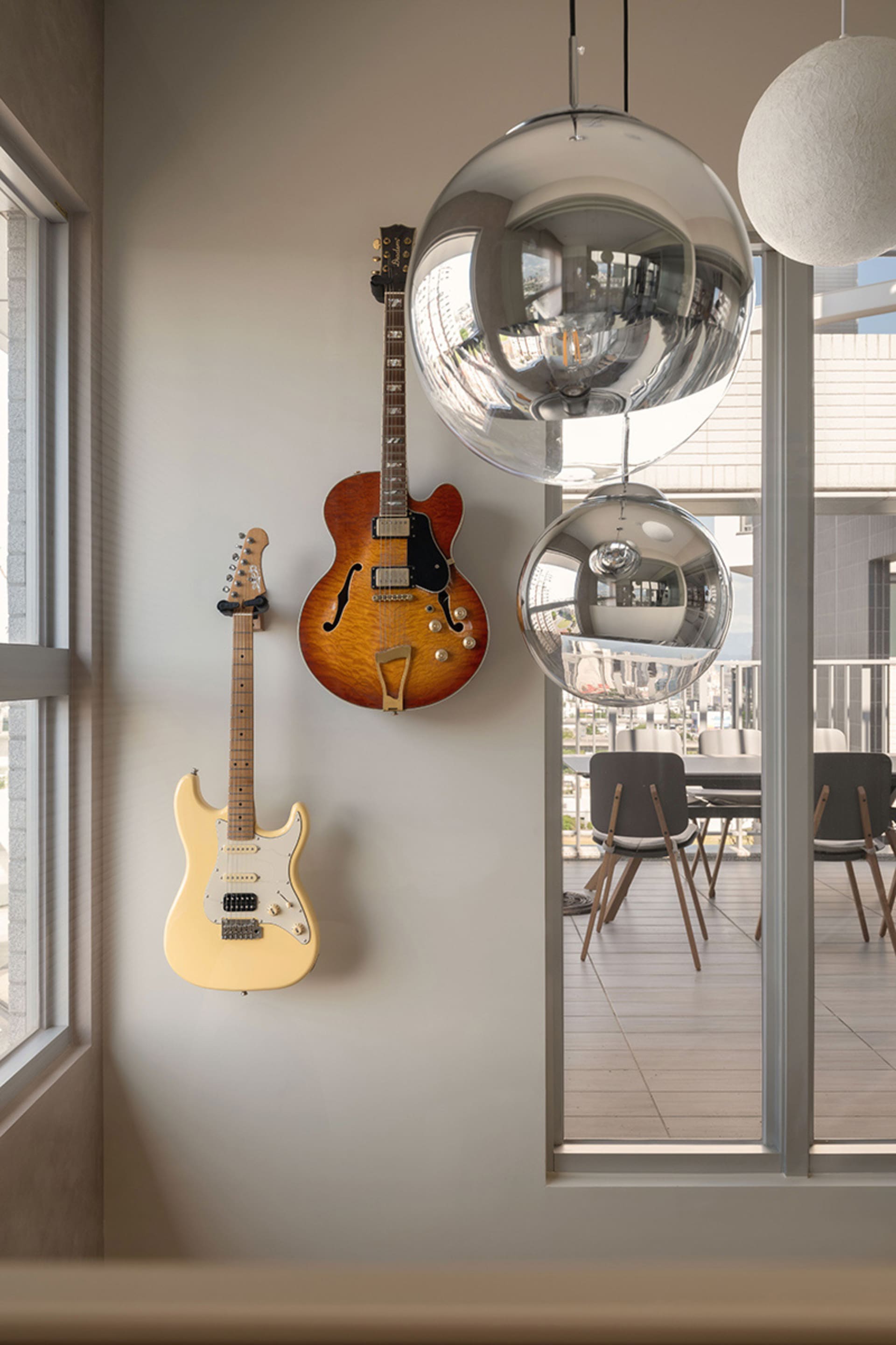A modern living room featuring a hanging electric guitar, a hanging electric guitar in a semi-hollow body style, and a hangin