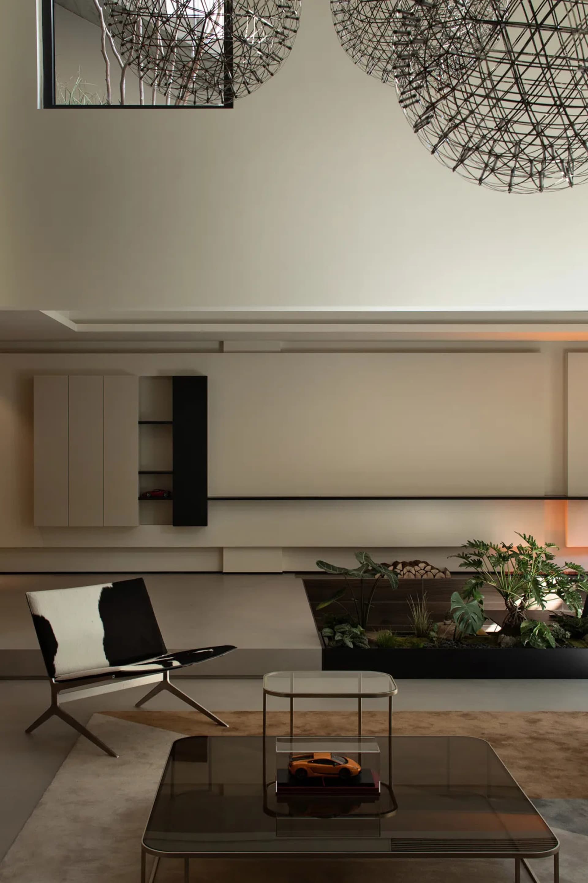 A modern living room with minimalist design featuring neutral tones and a large indoor plant.
