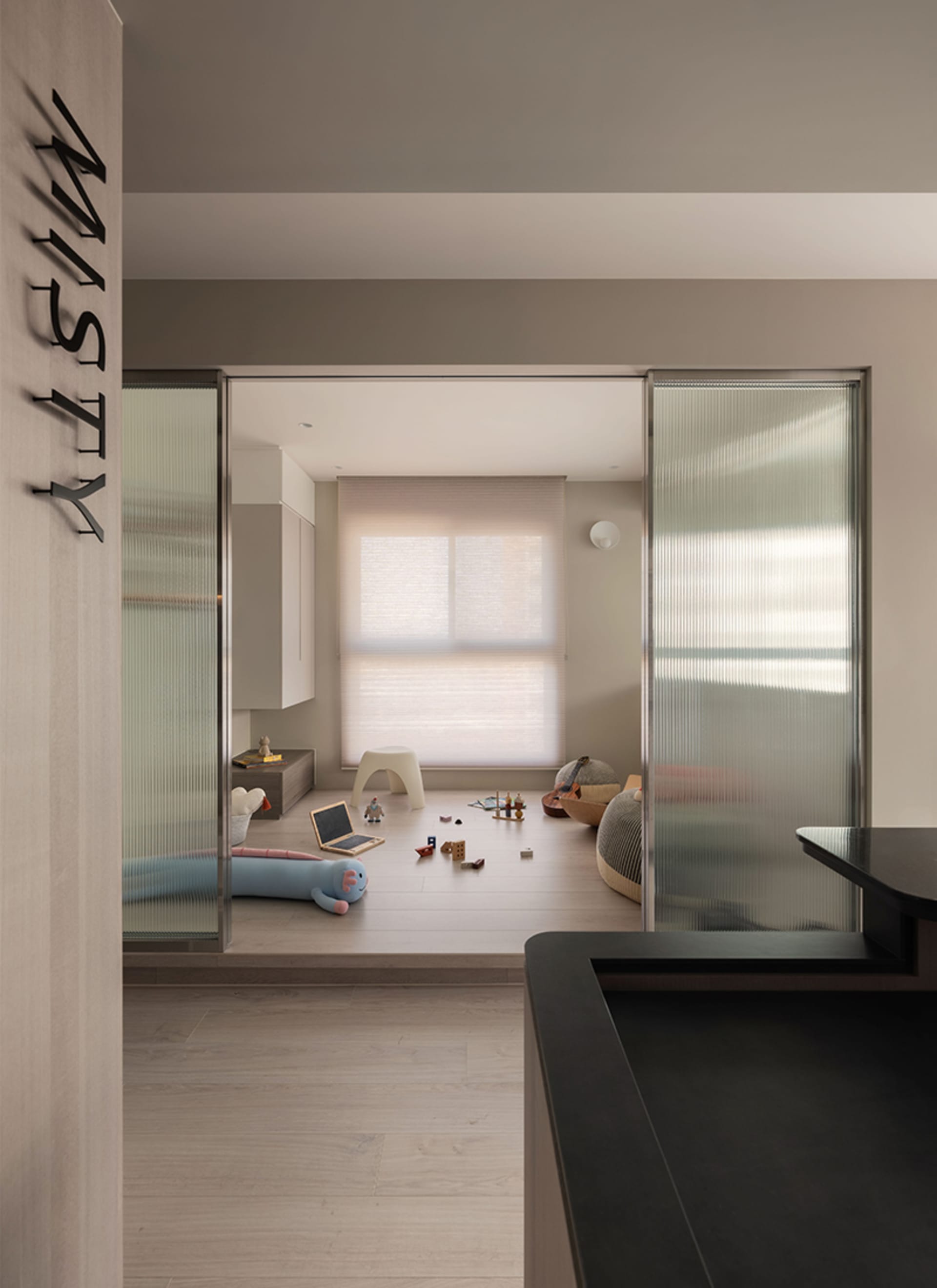 A modern residential playroom featuring wooden flooring, steel furniture, and glass doors.