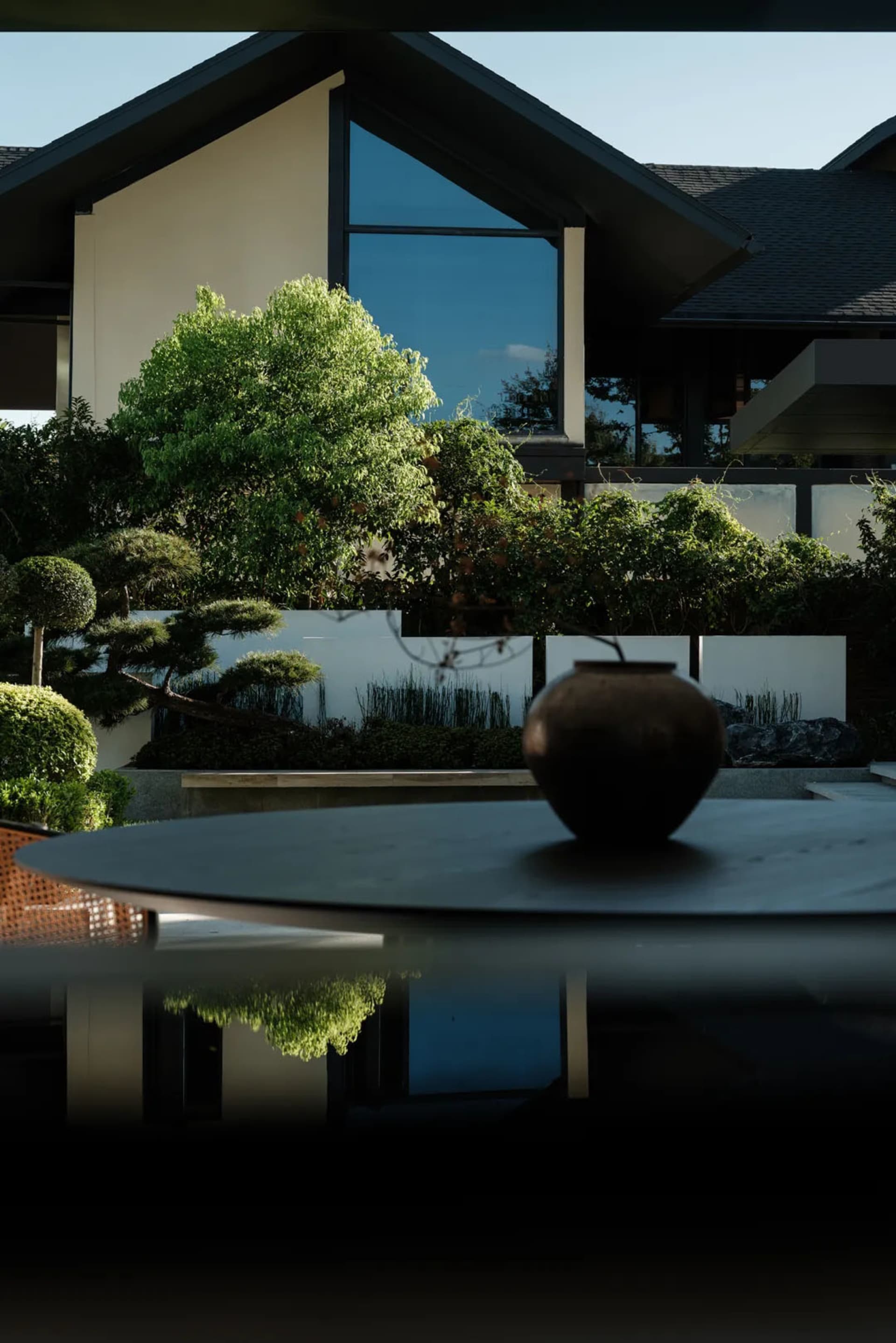 A modern residential exterior featuring large glass windows, stone accents, and wooden elements.