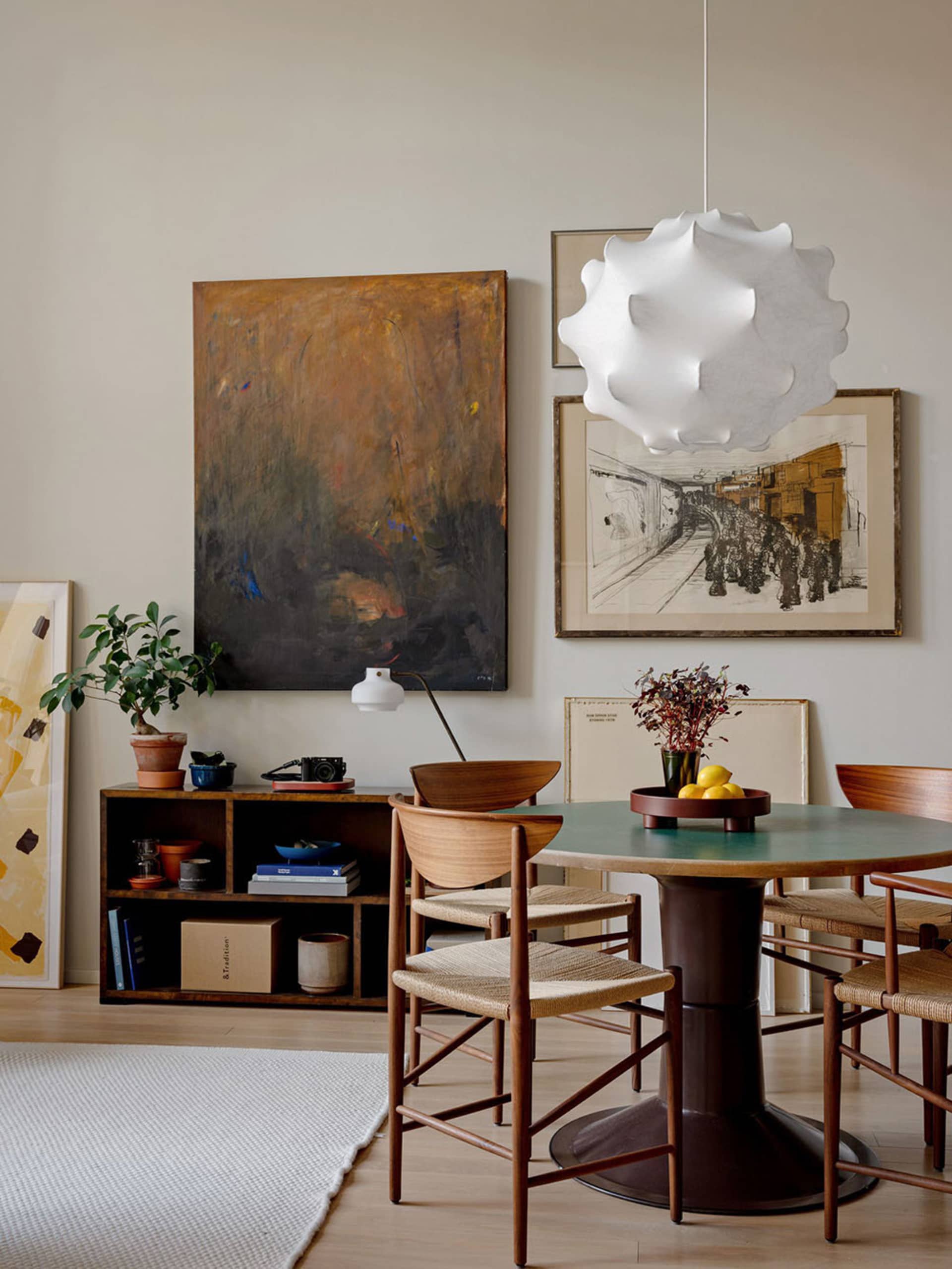 A minimalist dining room featuring wooden chairs and a metal pedestal dining table.