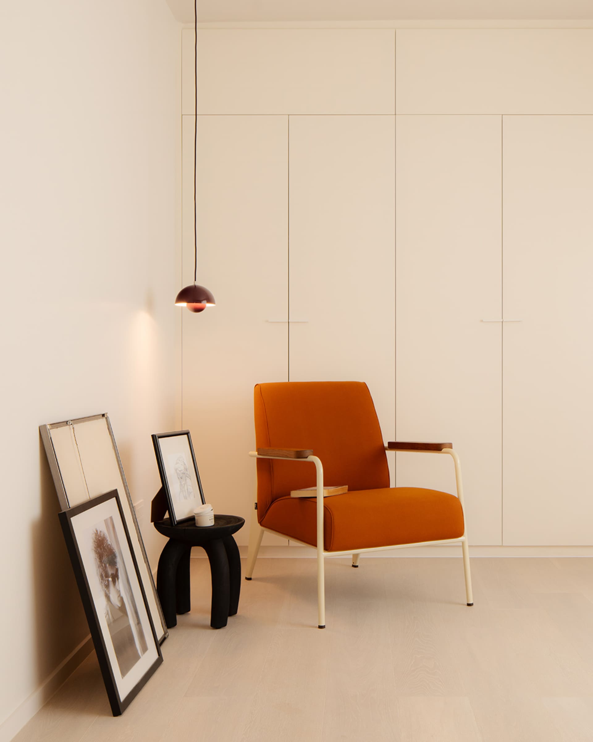A minimalist living room featuring an orange upholstered armchair with wooden accents.
