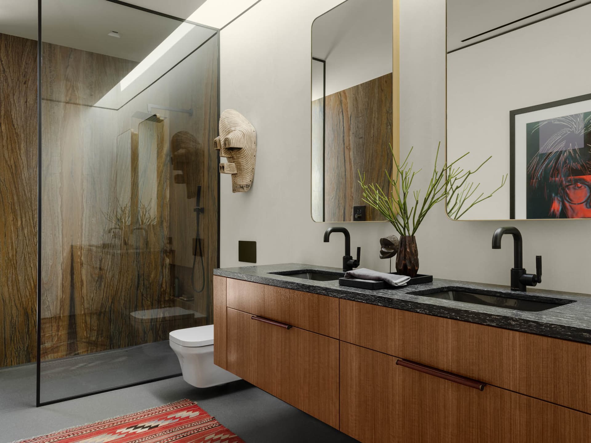 A modern bathroom featuring a wooden vanity, black sinks, and a glass shower enclosure.