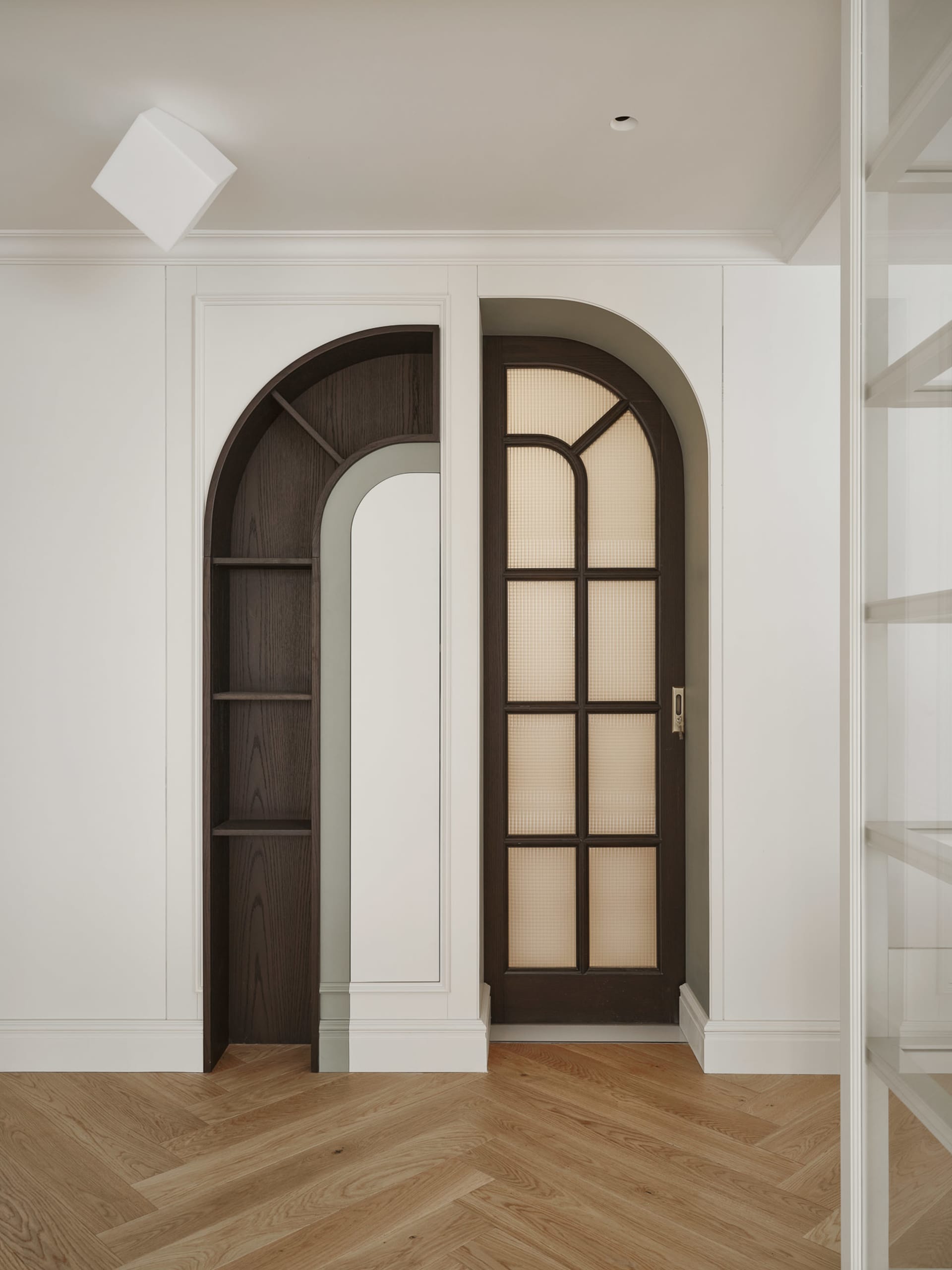 A modern home library with dark wood paneling and arched doorways.