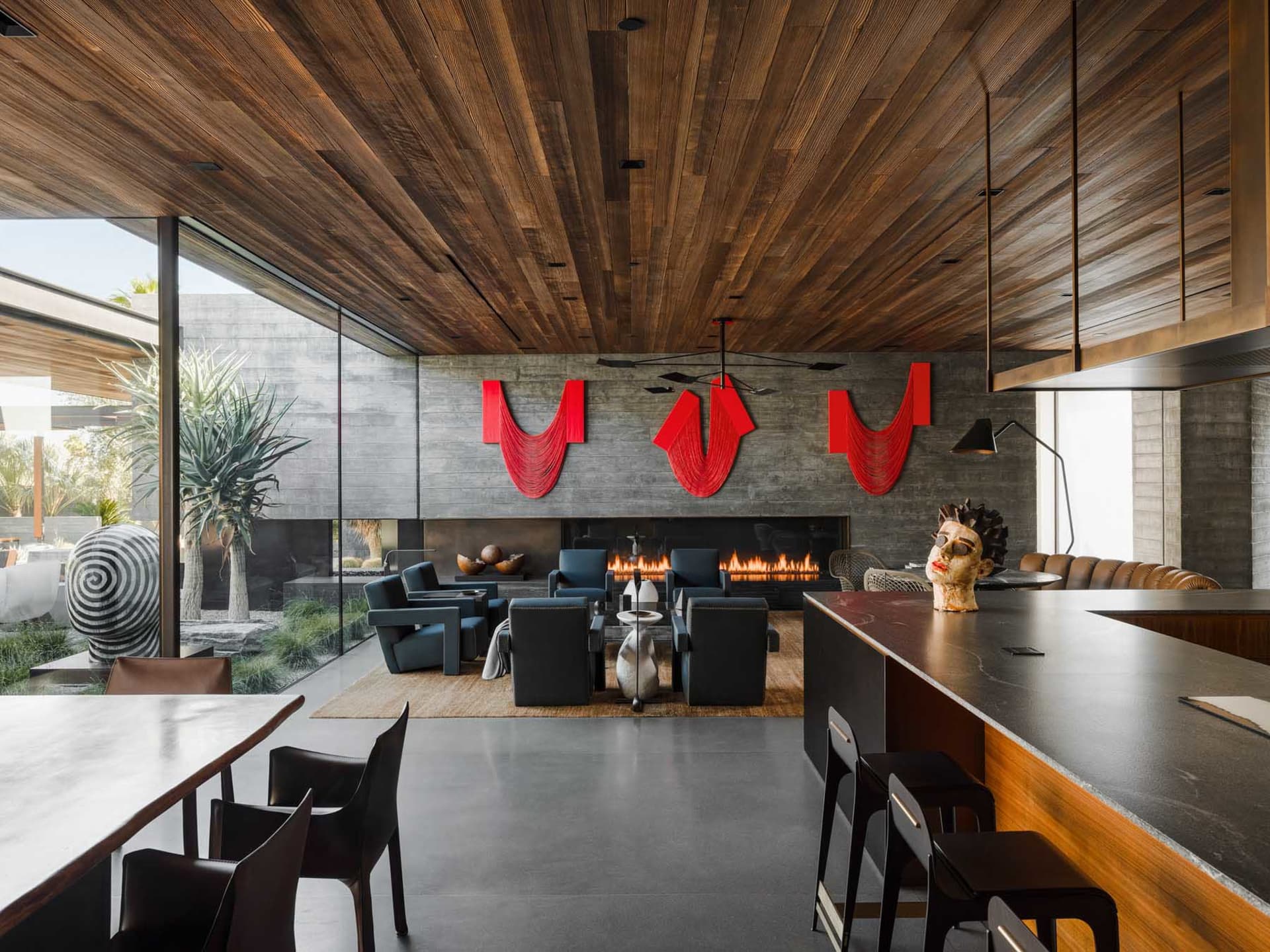 A modern living room with concrete walls, a fireplace, and red decorative elements.