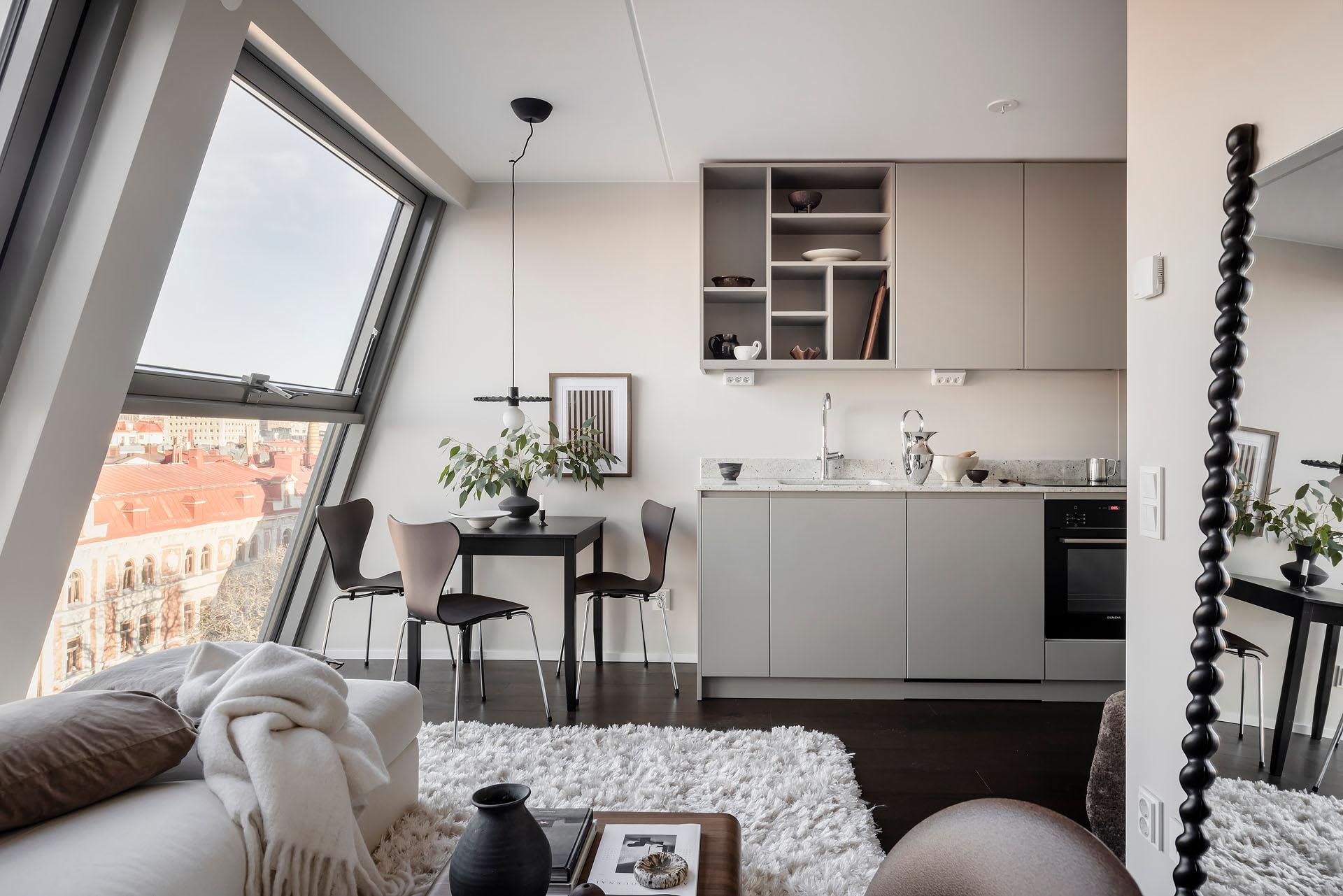 A modern, minimalist residential kitchen with white cabinets, a small dining table, and a sink