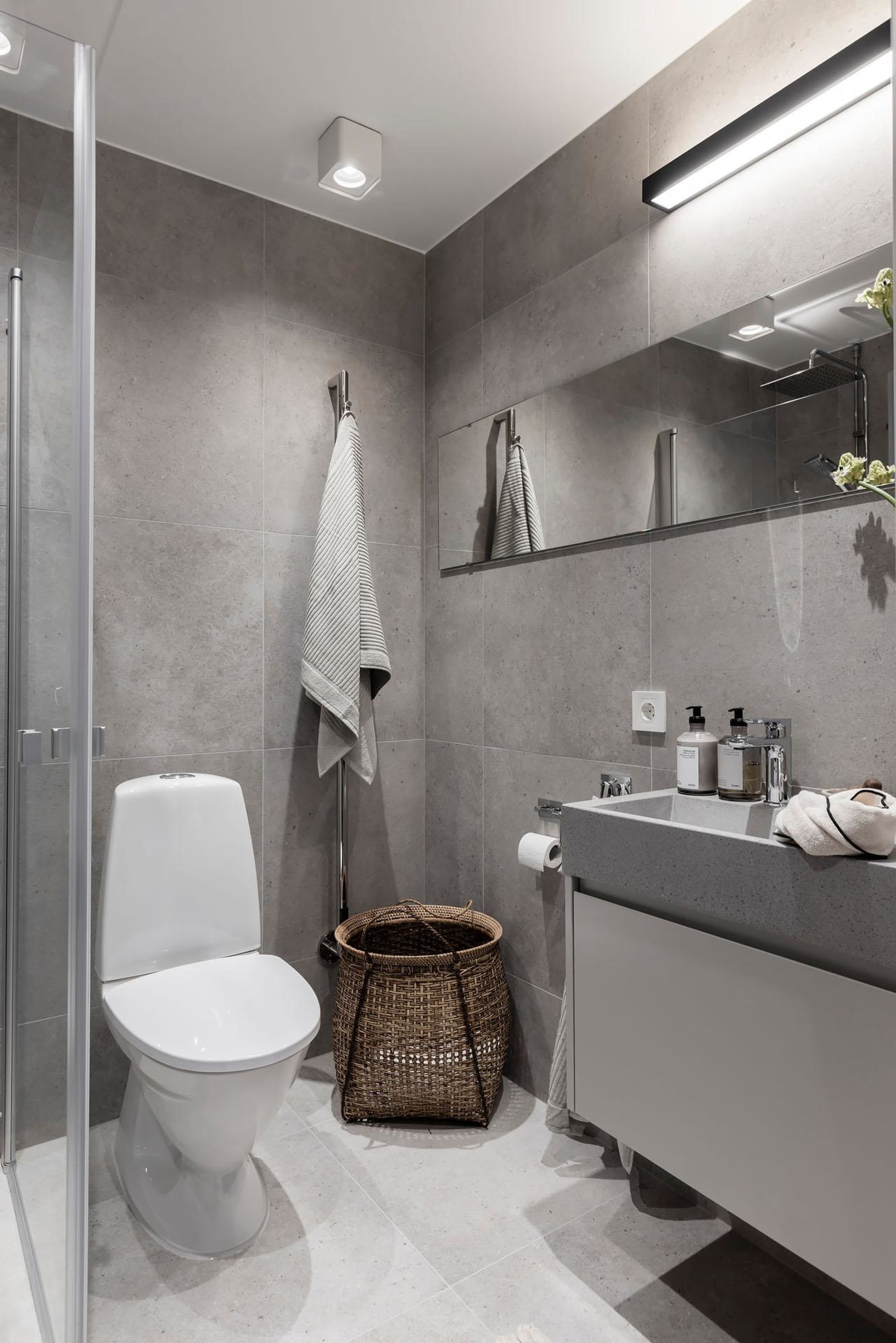 Modern bathroom with minimalist design, featuring concrete walls and floor, a floating vanity, and a walk-in shower.