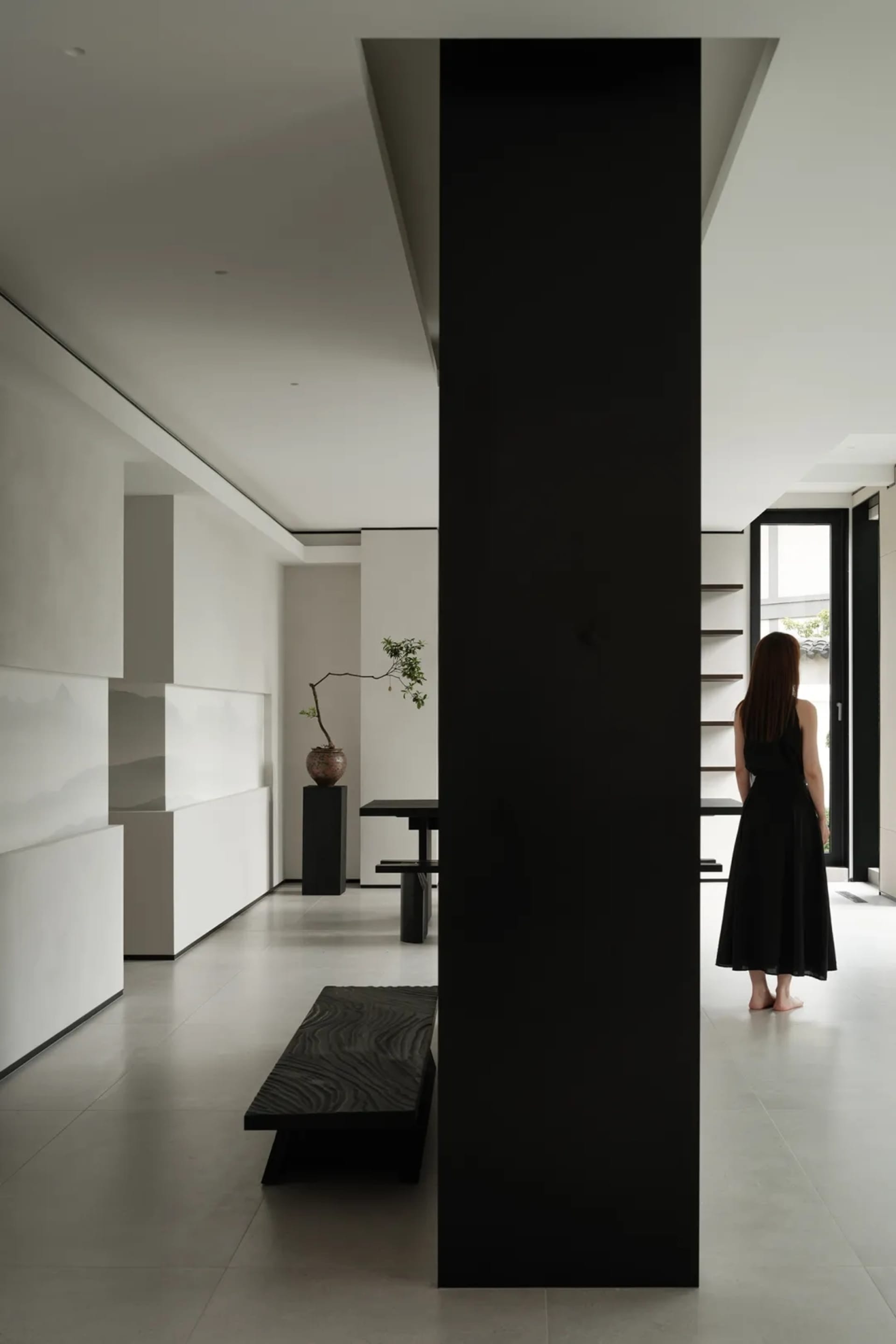 A modern living room featuring concrete walls, a black pillar, and a sleek, minimalist design.