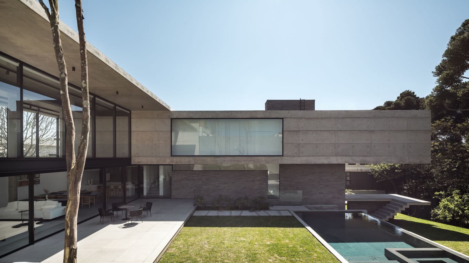 Modern house featuring concrete and glass exterior with large windows and patio.