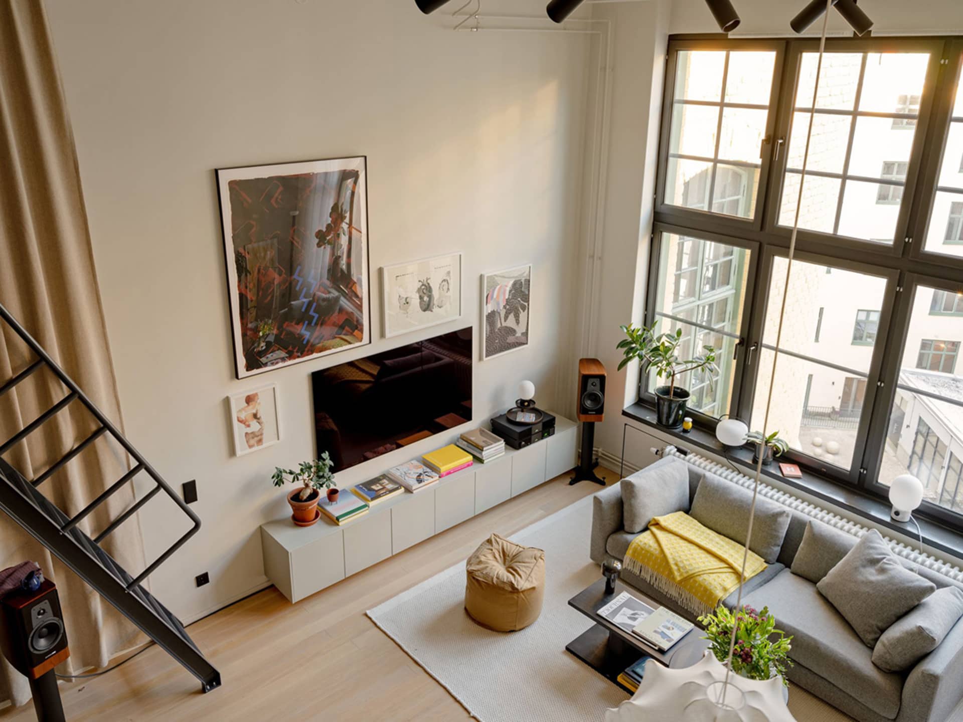 A modern living room with a grey couch, a plant, and a wooden floor.