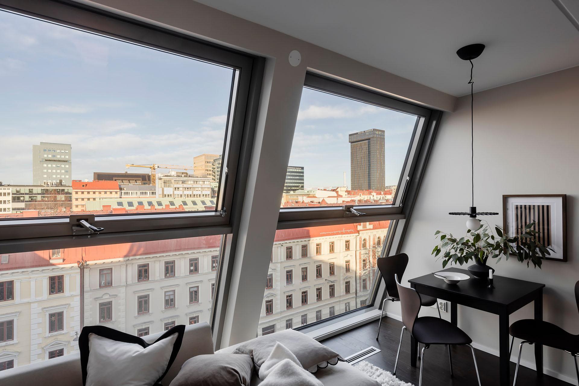A modern living room featuring glass window frames with a cityscape view.
