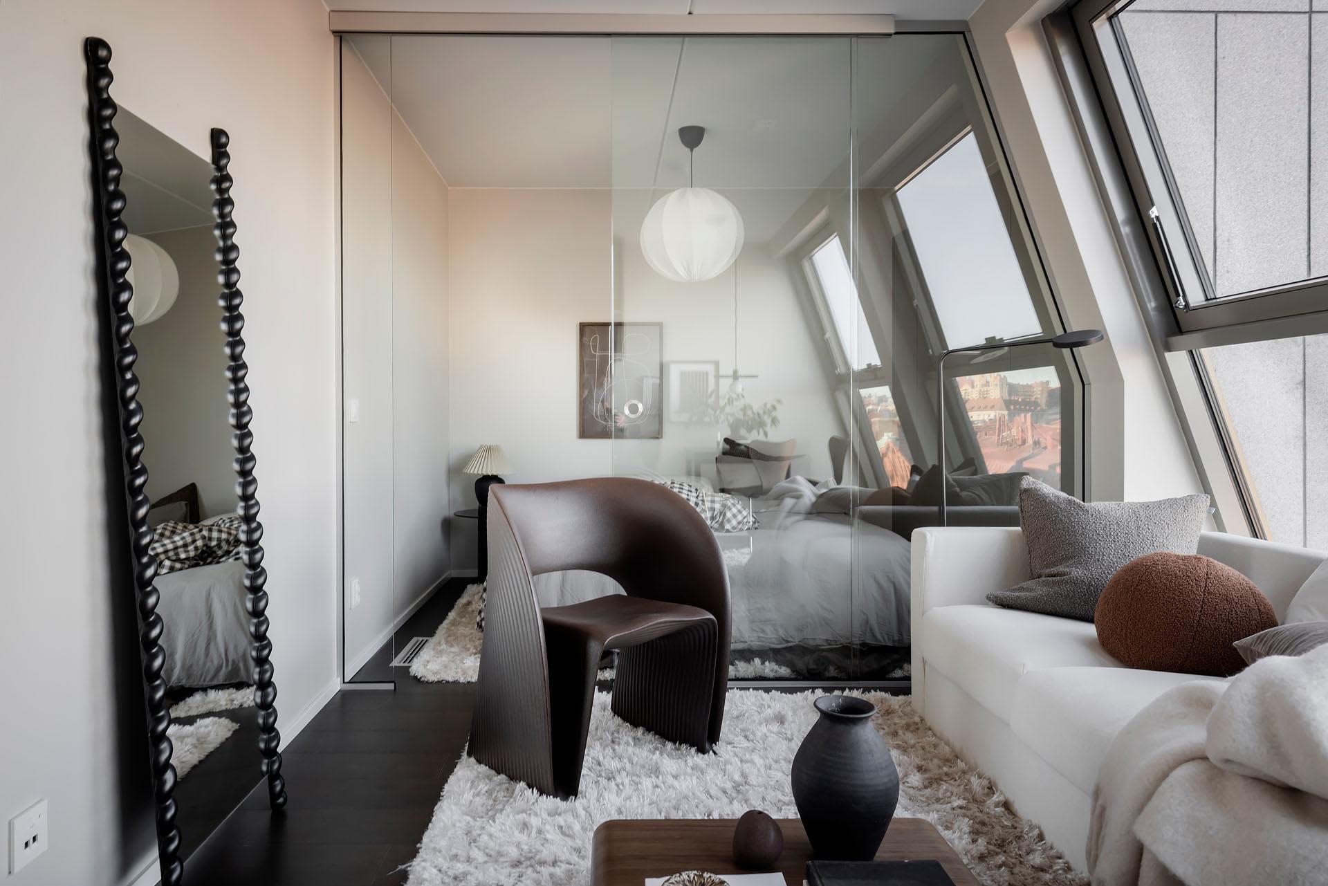 A modern living room with minimalist design, featuring dark wood flooring, a white sofa, and a large window with a city view.