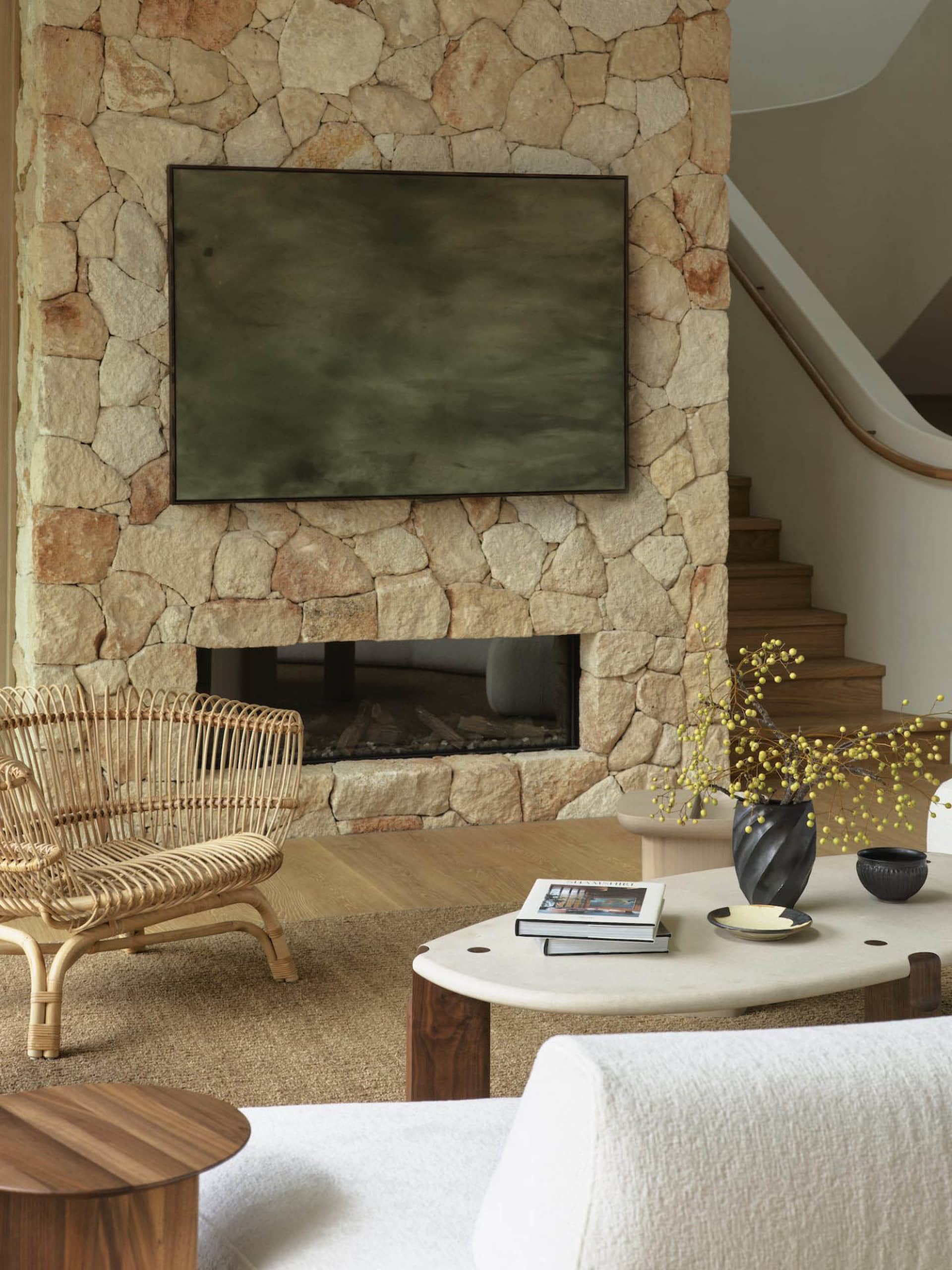 A modern living room featuring a stone fireplace and a flat-screen TV mounted above it.