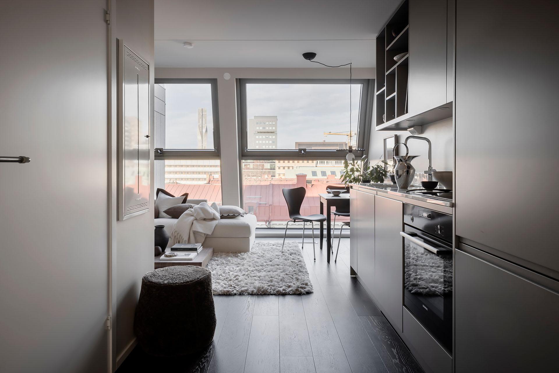 Modern minimalist apartment with black walls, white cabinets, and glass windows.