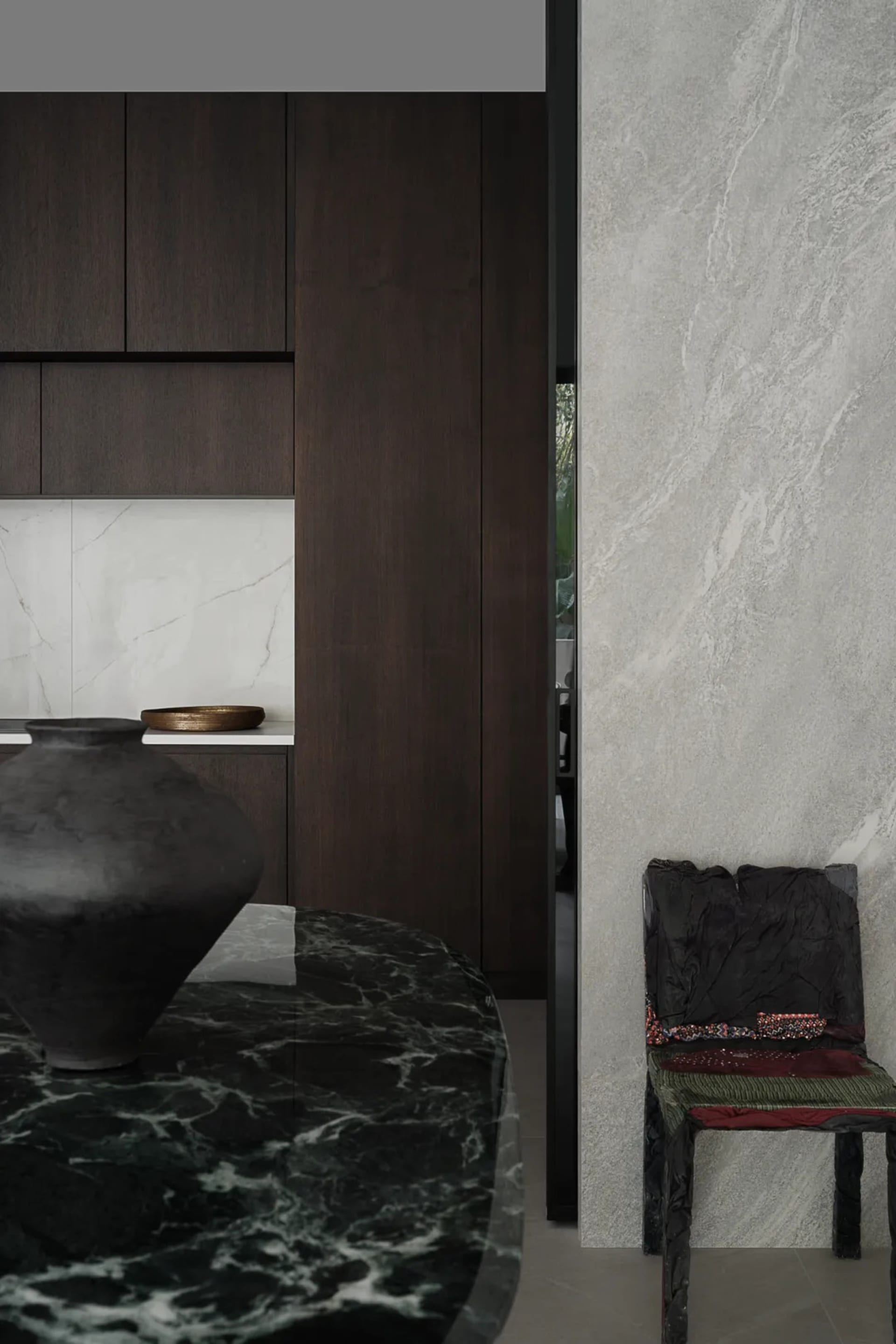A modern minimalist kitchen featuring a black marble countertop and a wooden chair.
