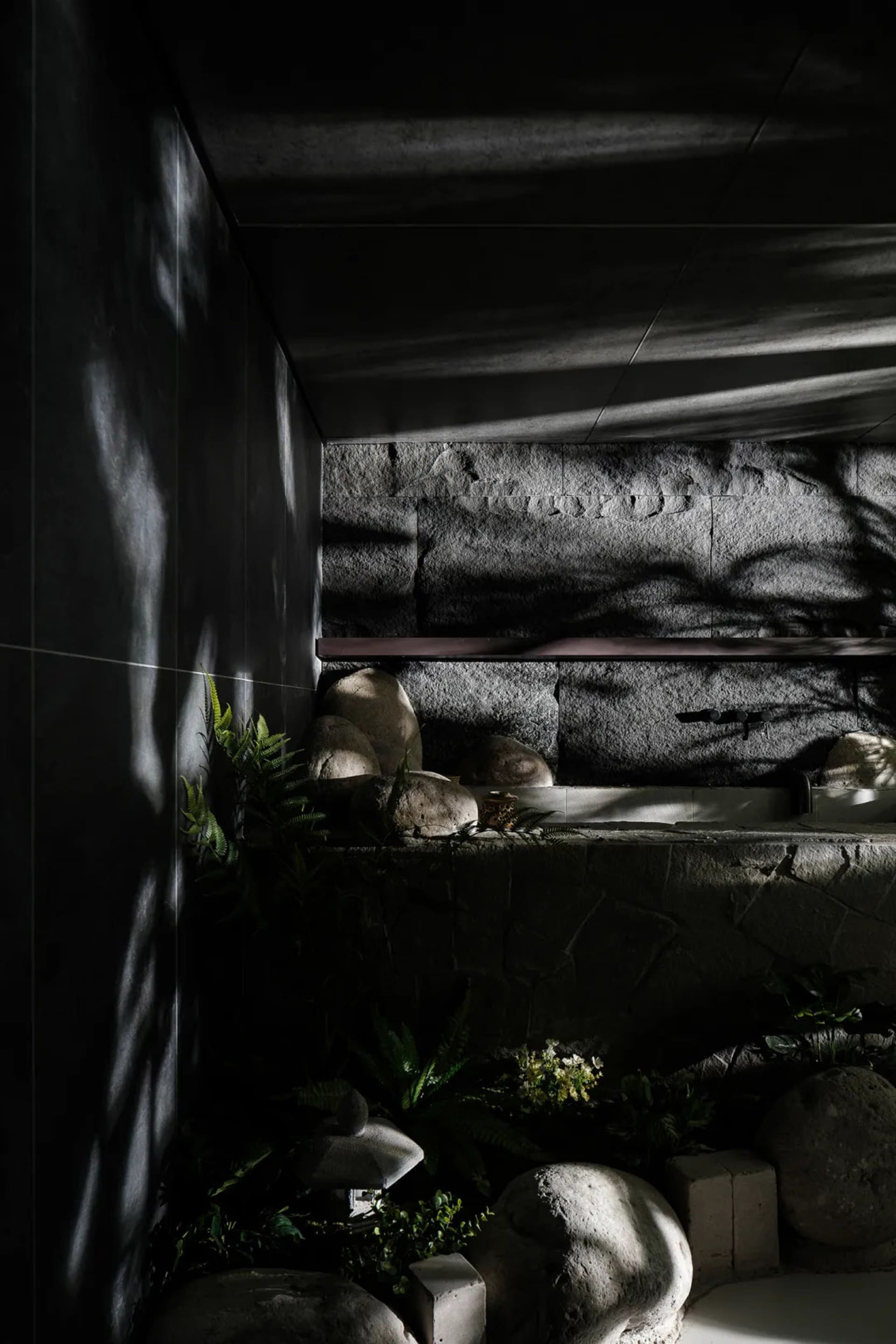 A minimalist concrete bathroom features natural light and rock elements.