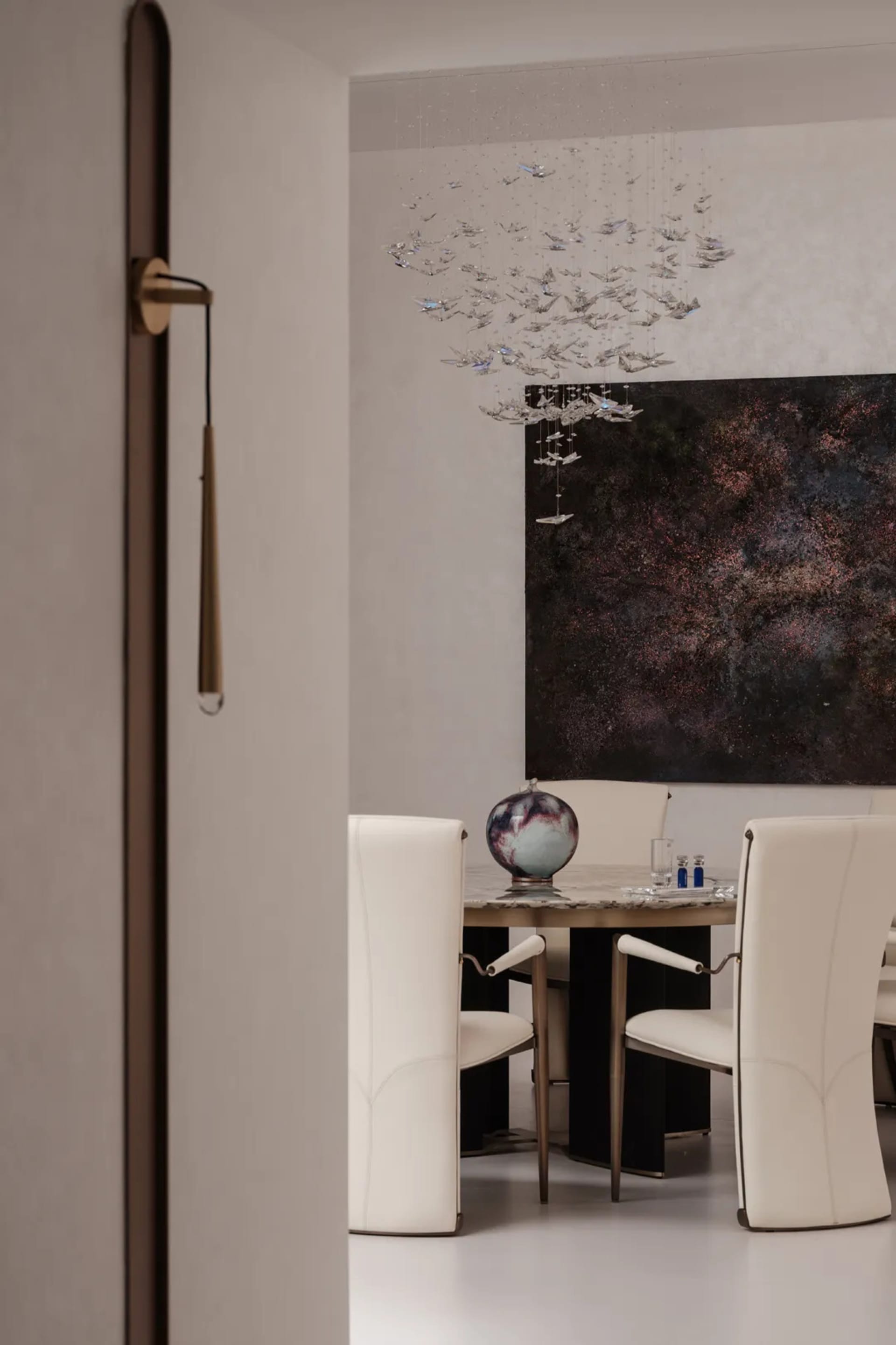 A modern dining room featuring a marble table and chandelier.