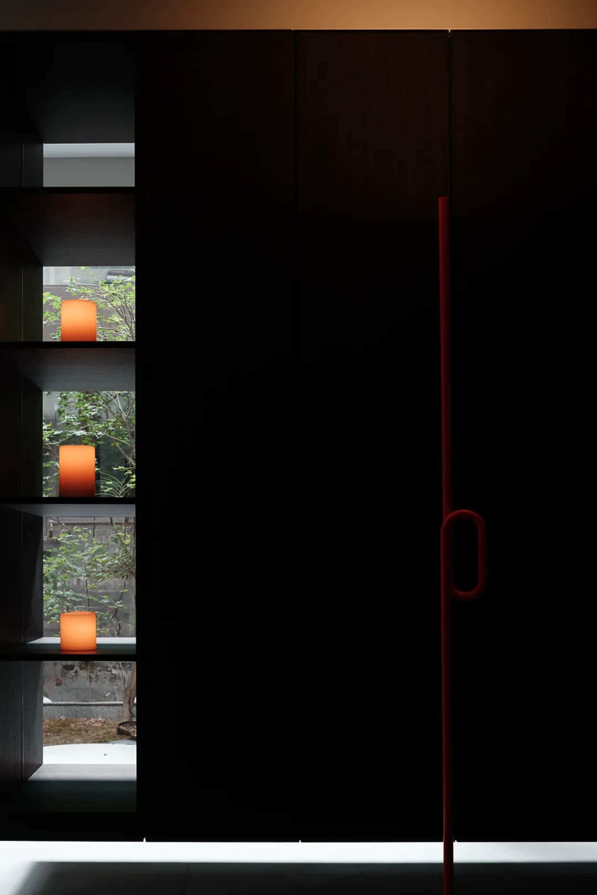 Modern interior with black wood panels and minimalist decor featuring illuminated candles.