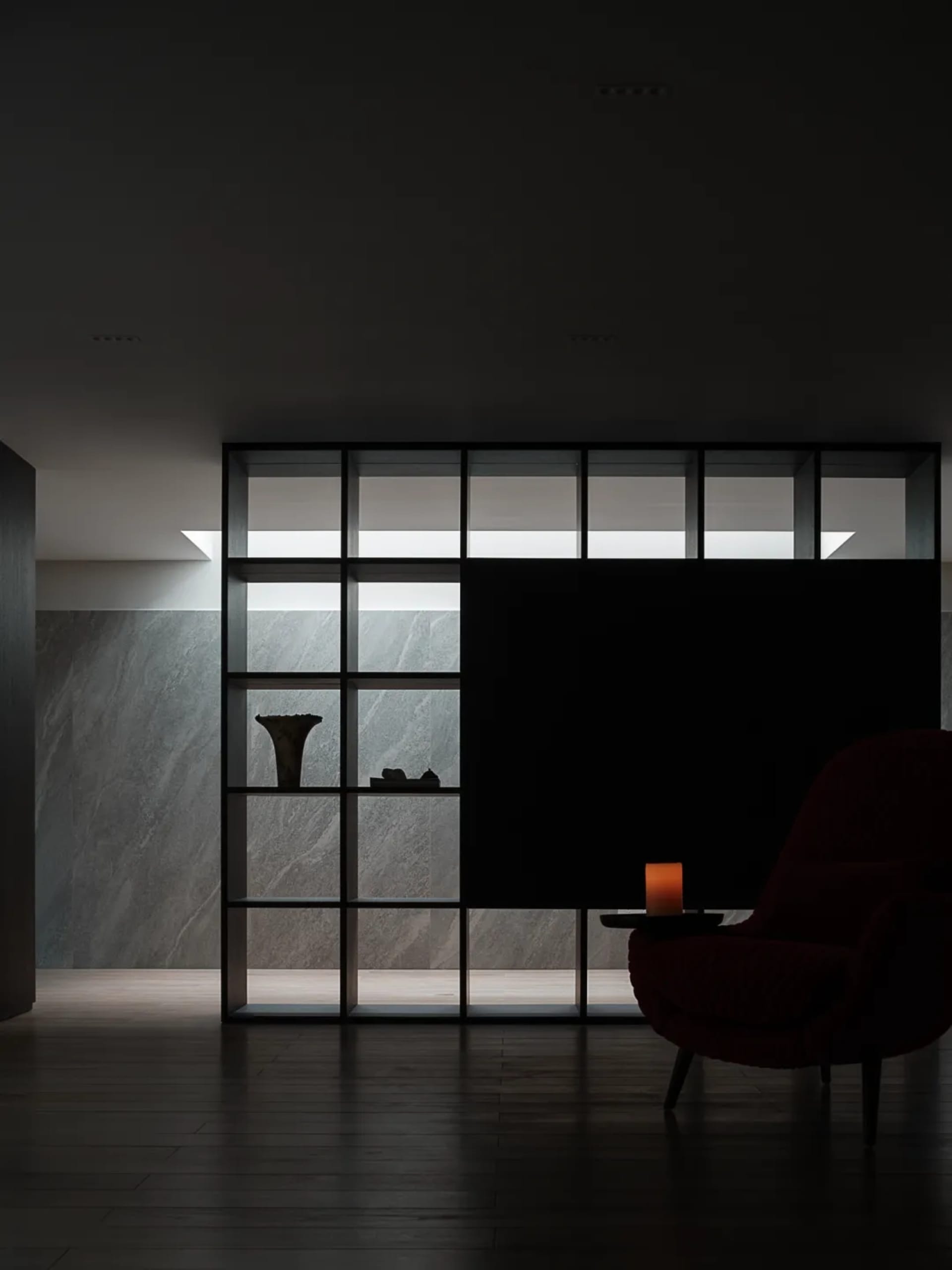 Modern lobby with marble floor and wall, featuring a red armchair.
