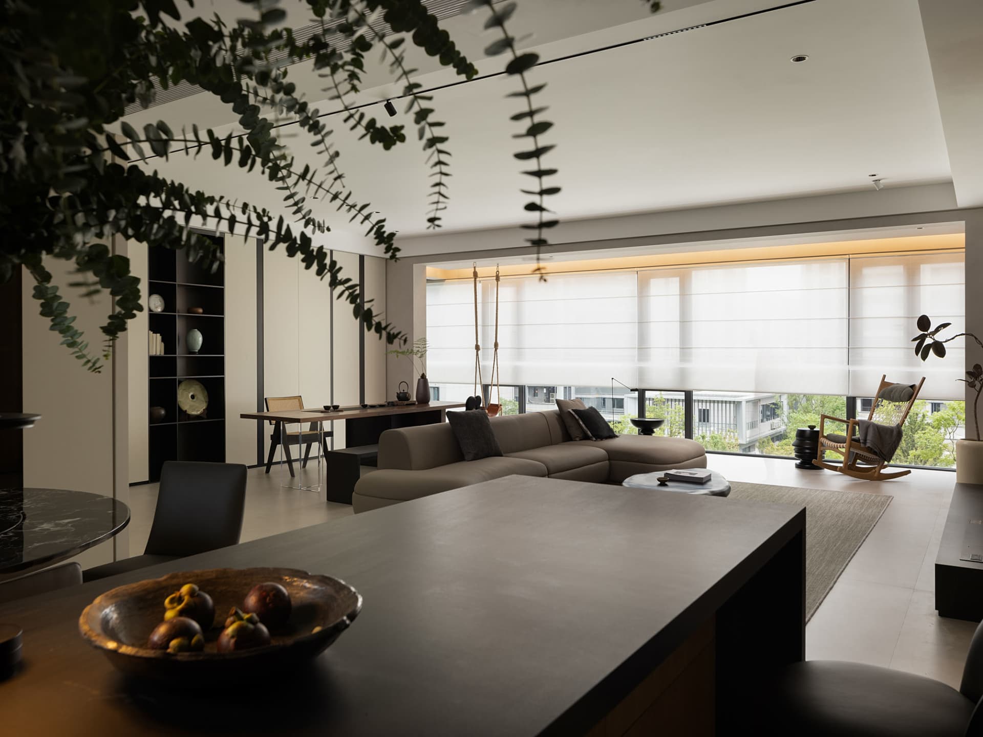 A minimalist living room with neutral furniture and a large window.