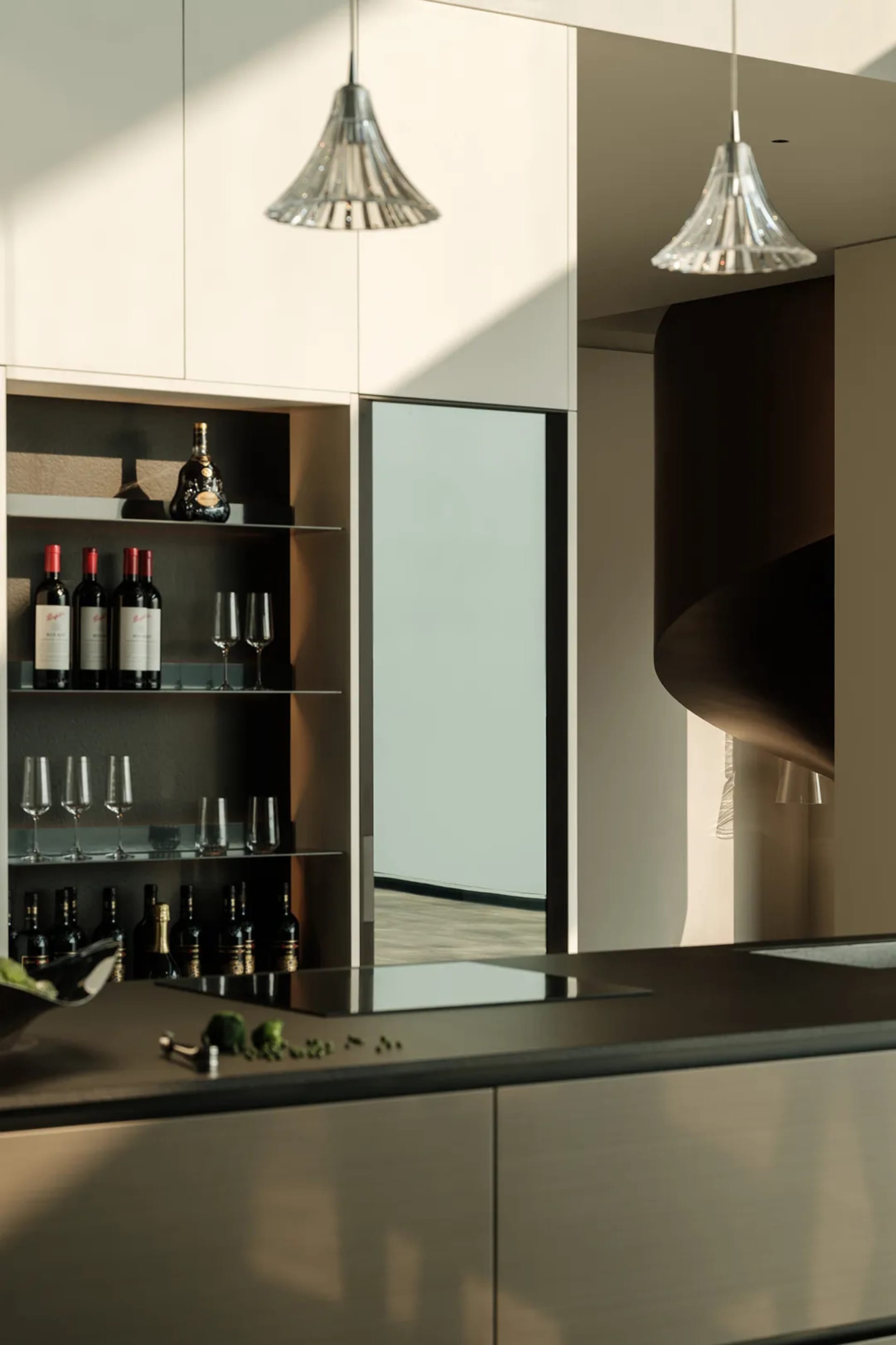 Modern kitchen with metallic finishes and wine rack with glasses.