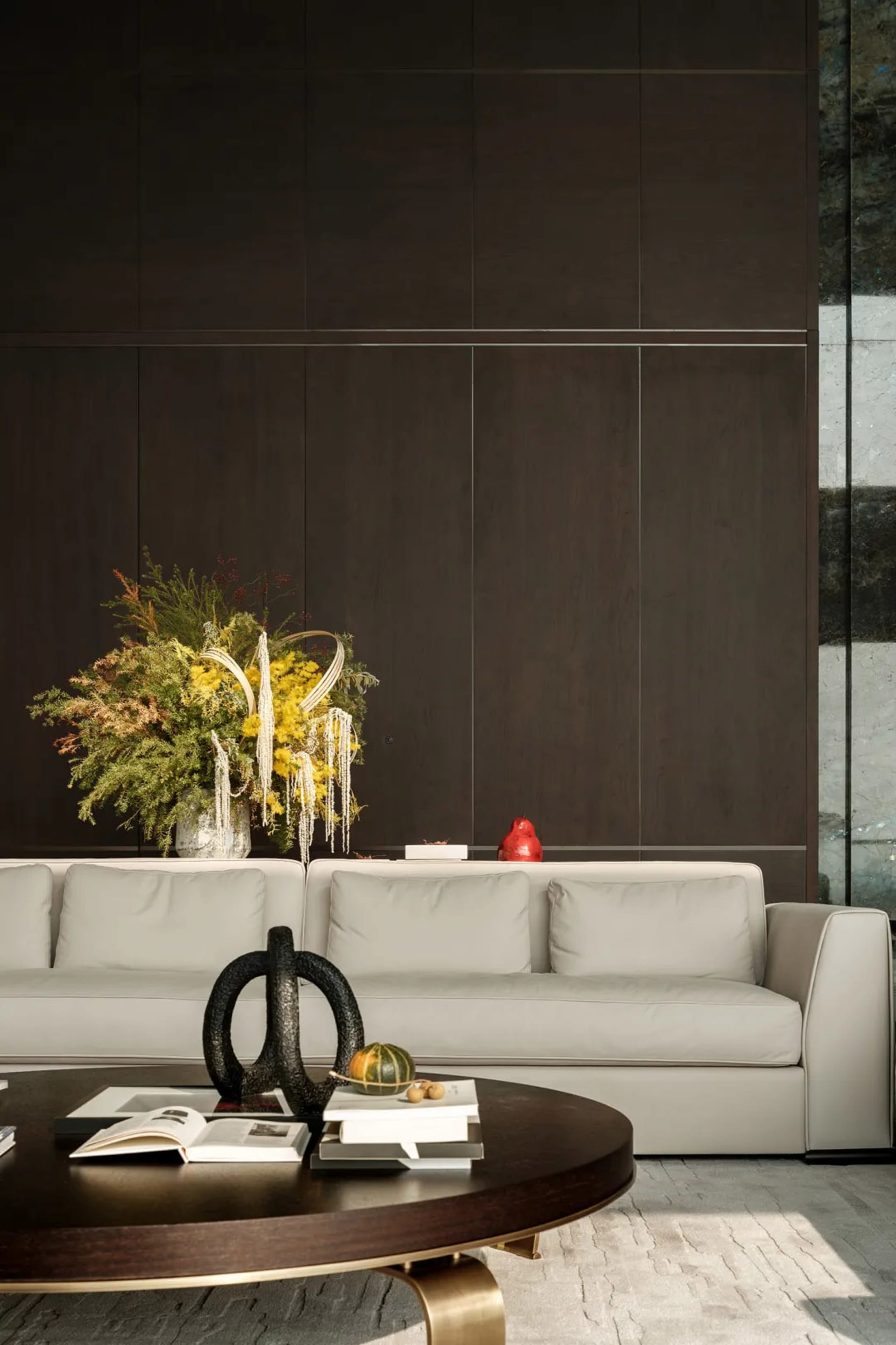 A modern living room with a beige sofa adorned with a large, vibrant flower arrangement and various decorative items on the c