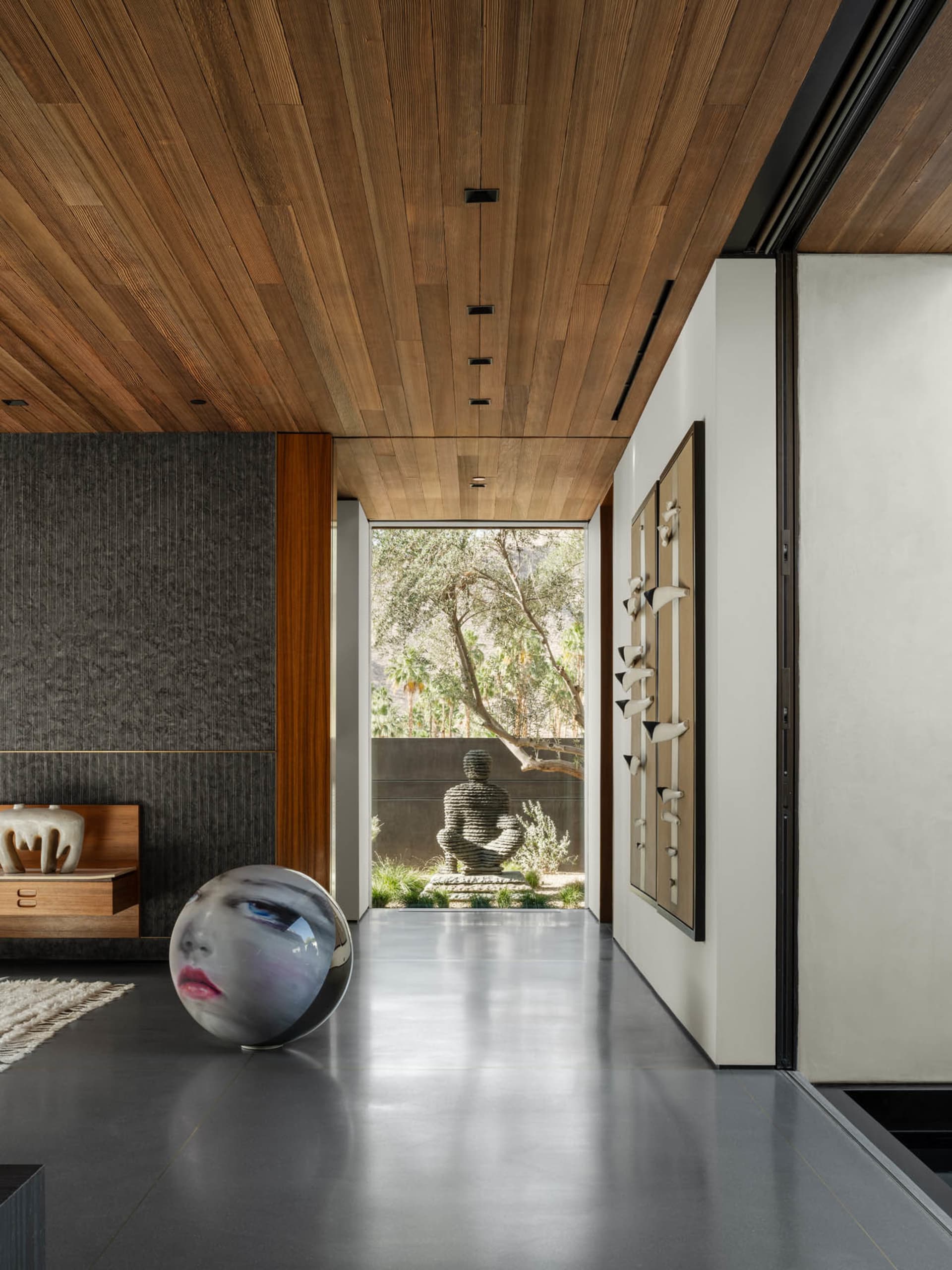 Modern living room with concrete floors, glass walls, and minimalist decor.