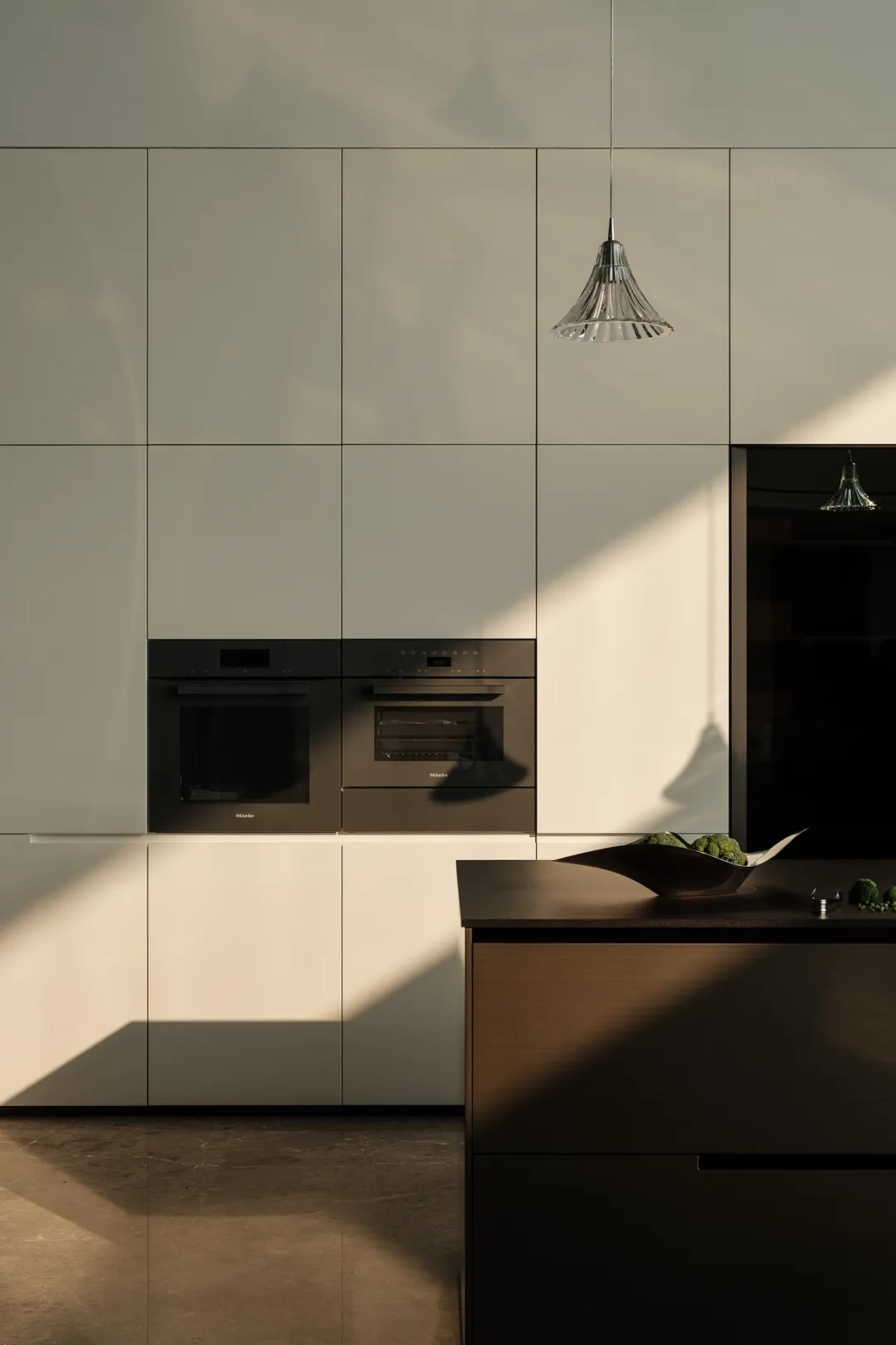 Modern, minimalist-style kitchen with sleek, dark cabinetry and stainless steel appliances.