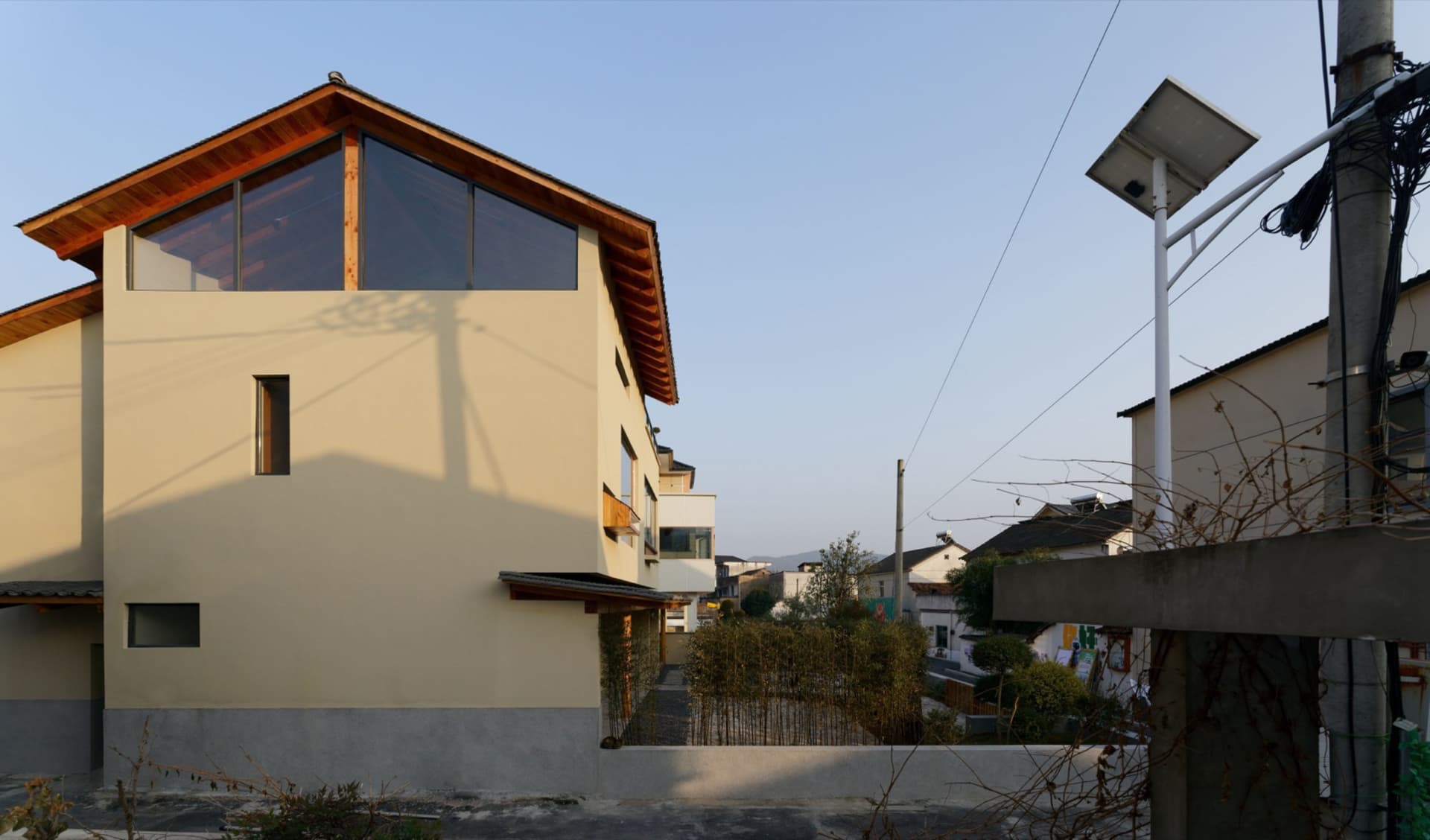 現代住宅外觀，混凝土立面、大型窗戶與斜屋頂。