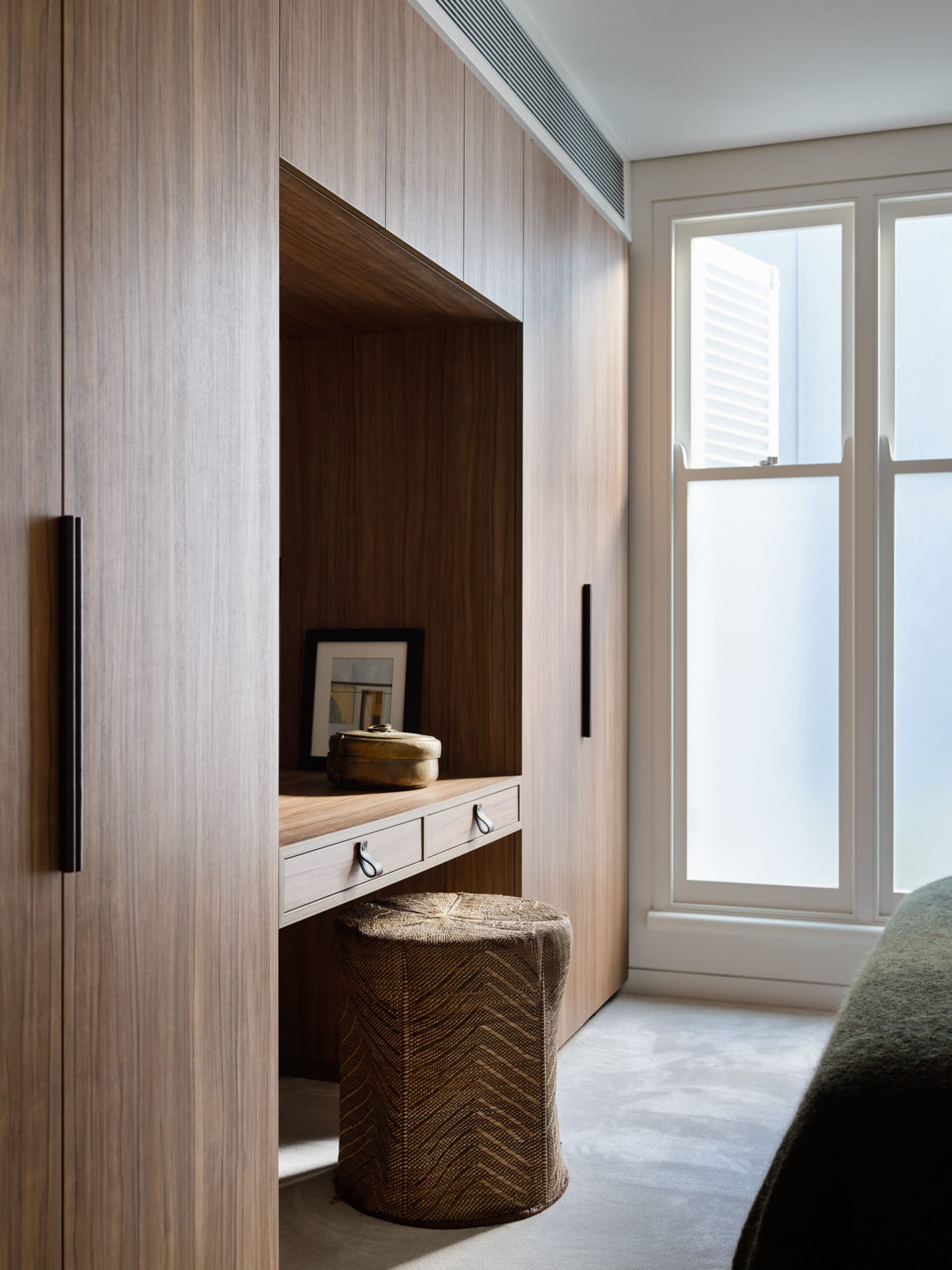 A minimalist bedroom dressng area with wooden paneling and a woven basket on the floor.