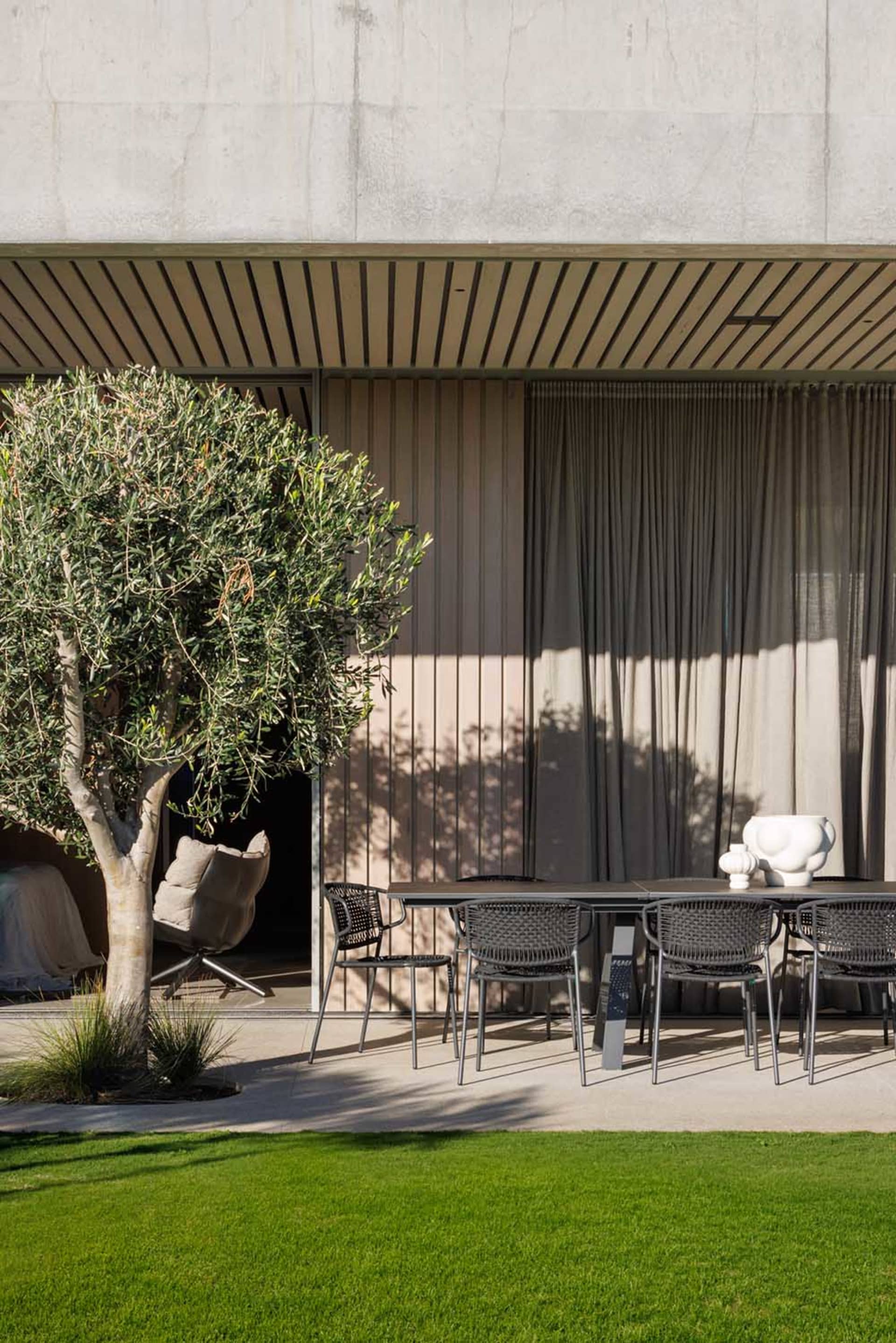 Modern patio with concrete floor, glass partition, and seating area.