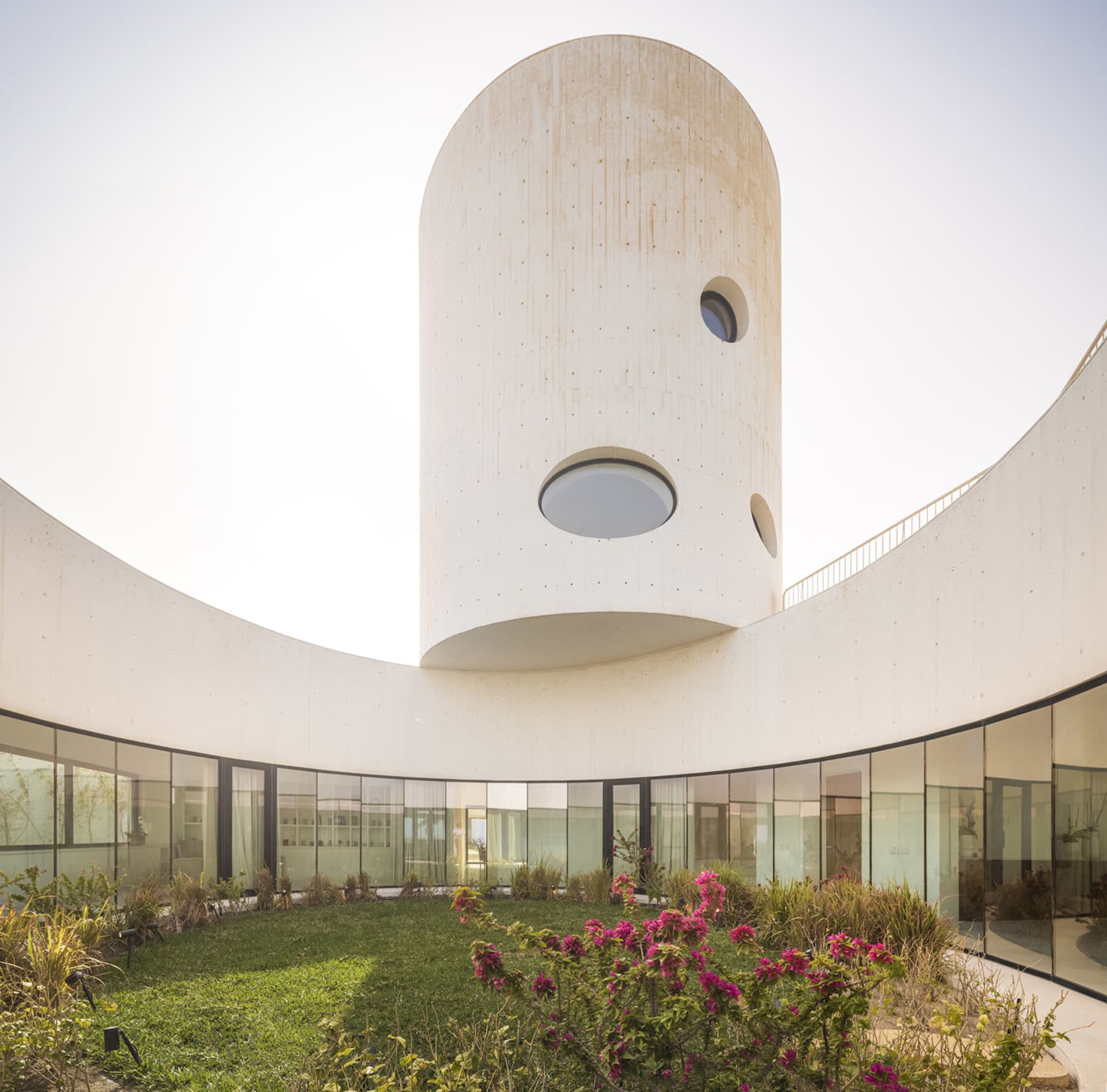 A modern residential interior with a circular concrete structure and a central courtyard.