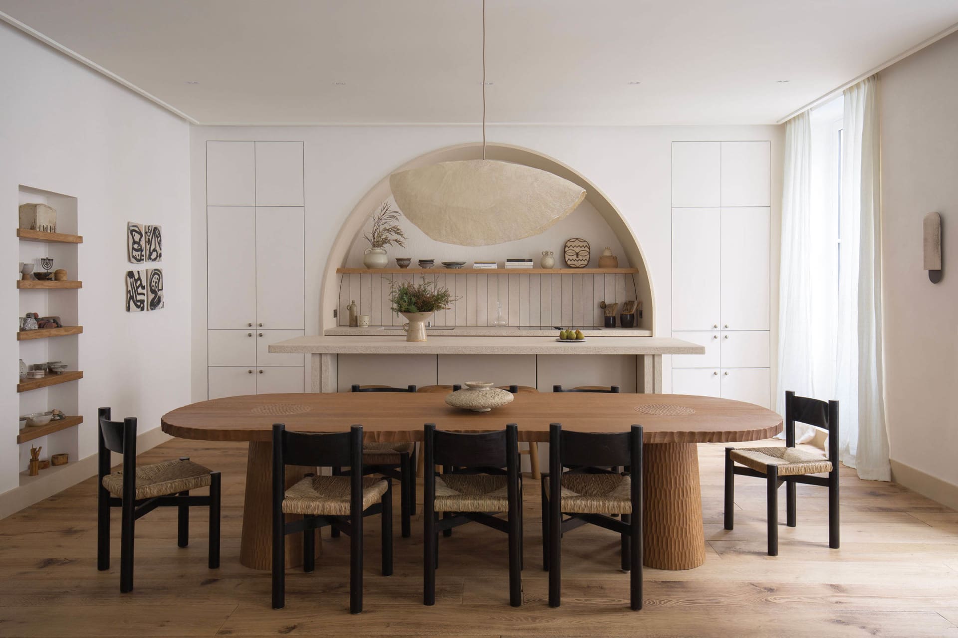 Modern minimalist kitchen with a stone table and wooden chairs.