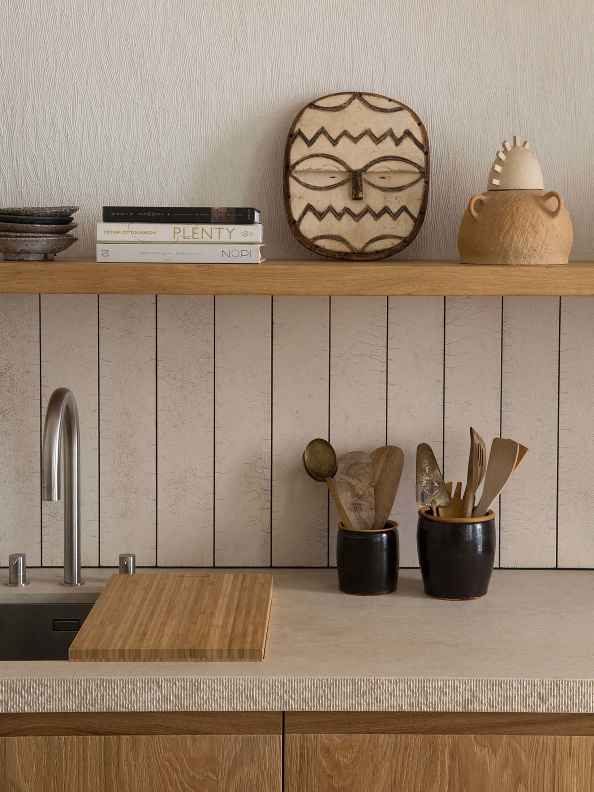 A modern kitchen with wooden cabinets, a ceramic vase, and a cutting board.