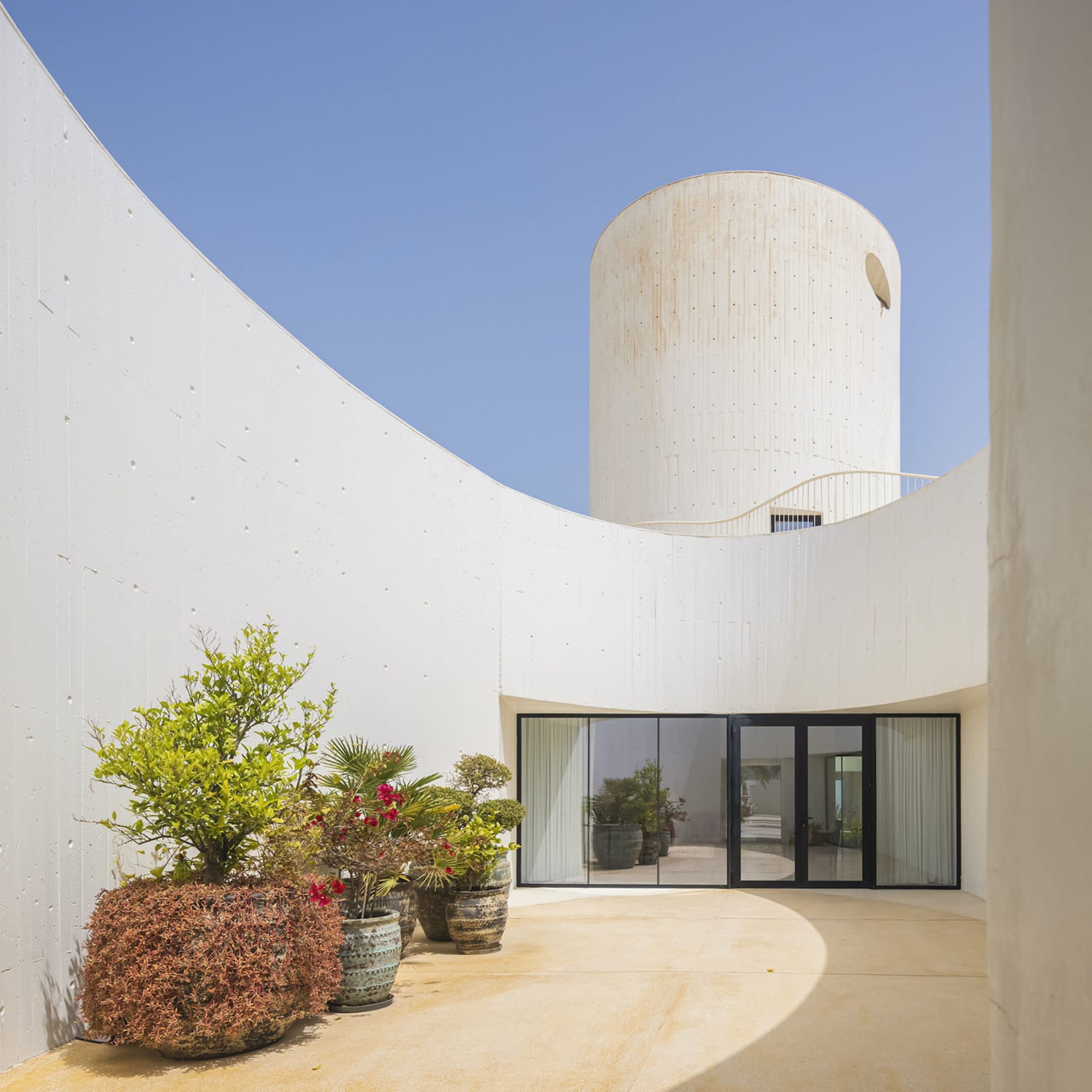 Modern, white architectural interior with concrete walls, open space, and glass doors.