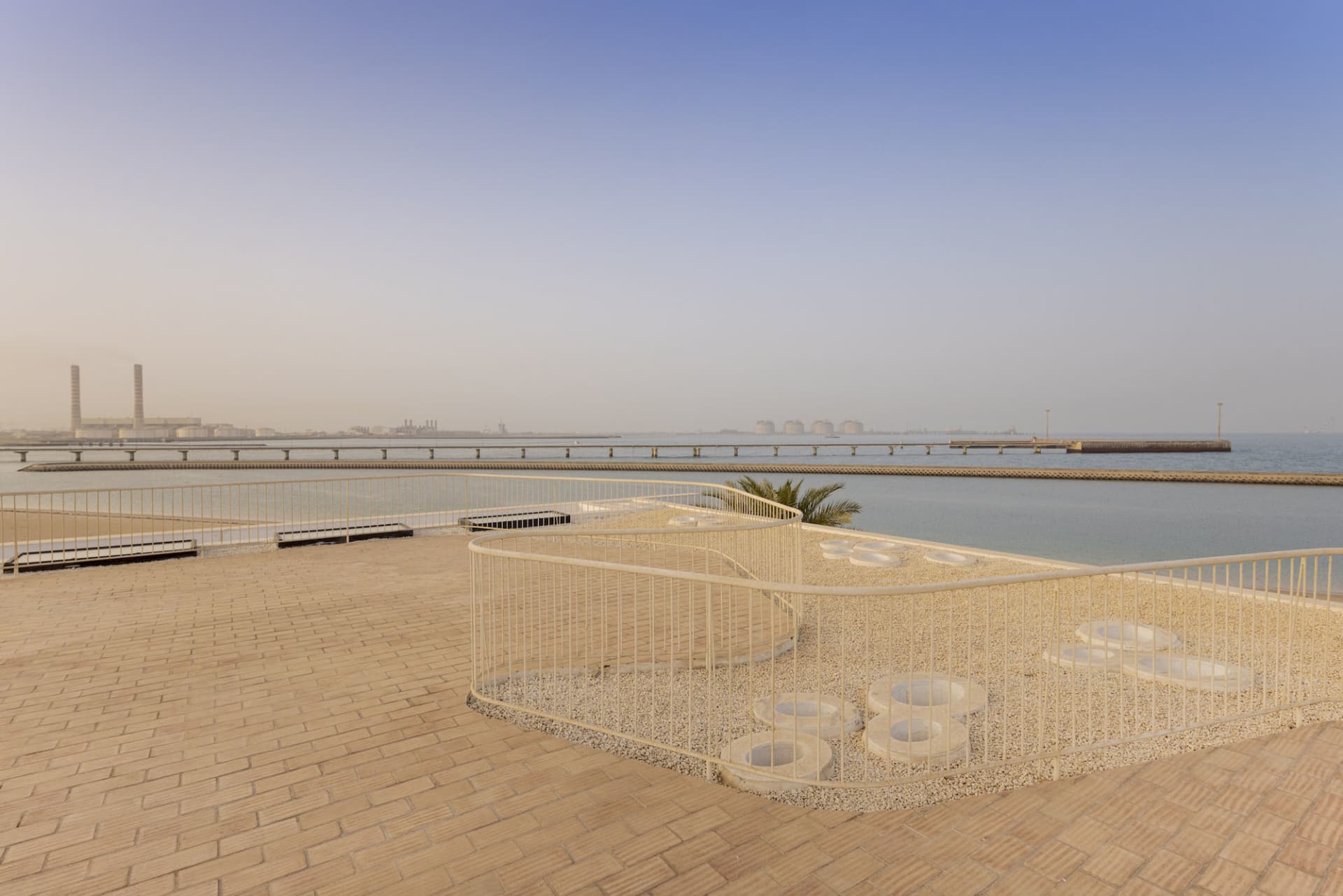 A sand-covered balcony overlooking the sea with a railing and a few circular platforms.